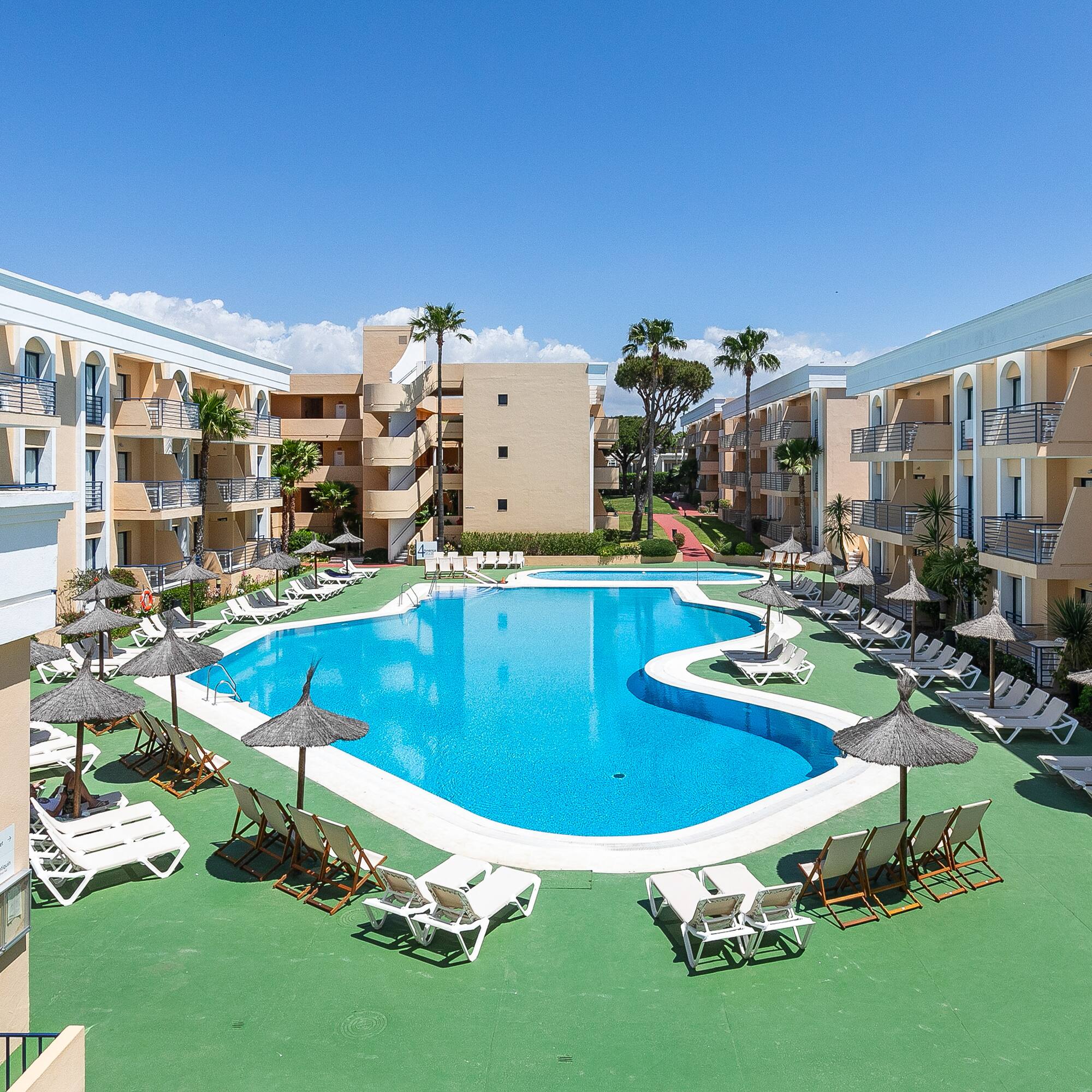 a pool with lounge chairs and umbrellas in front of buildings