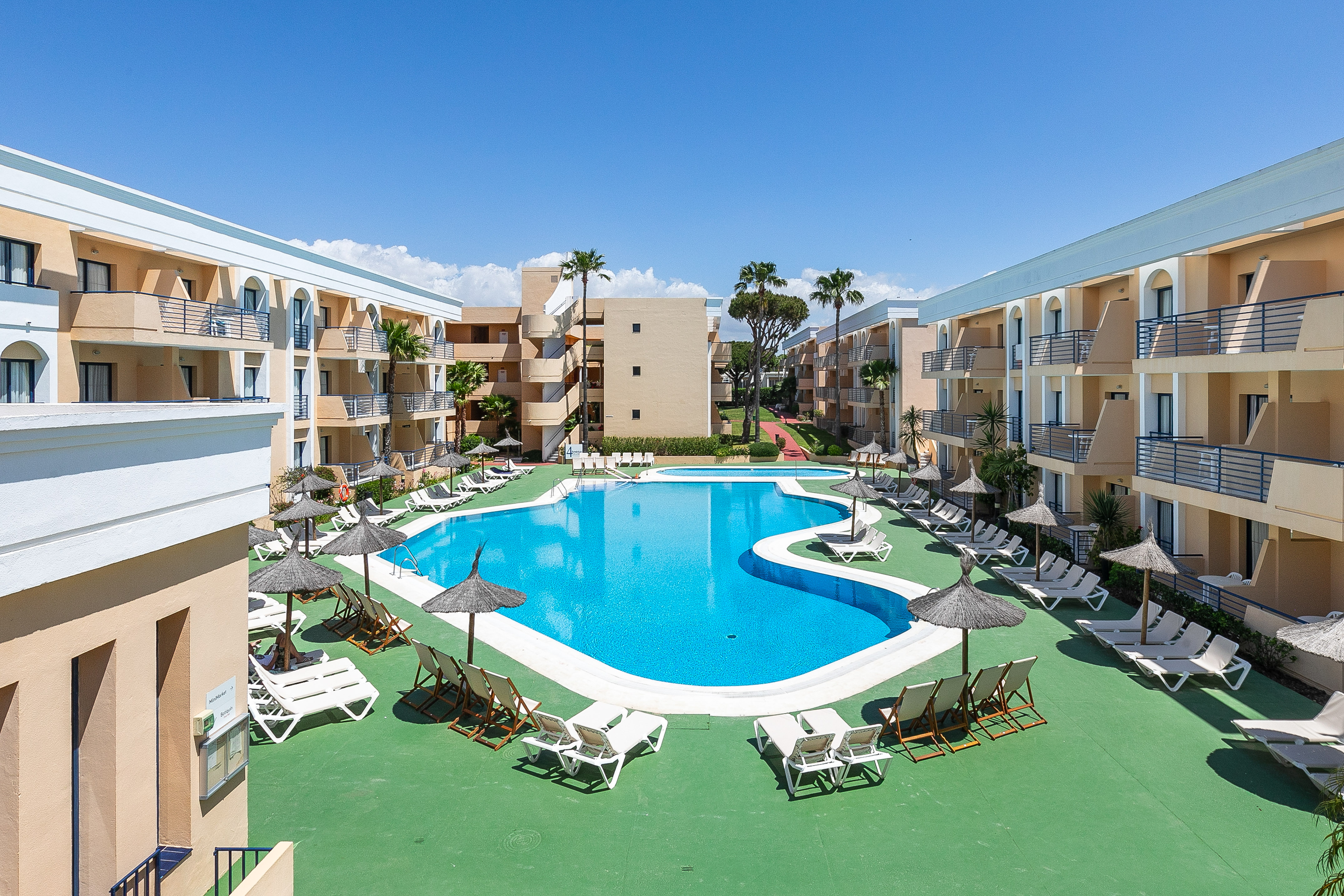 a pool with lounge chairs and umbrellas in front of buildings