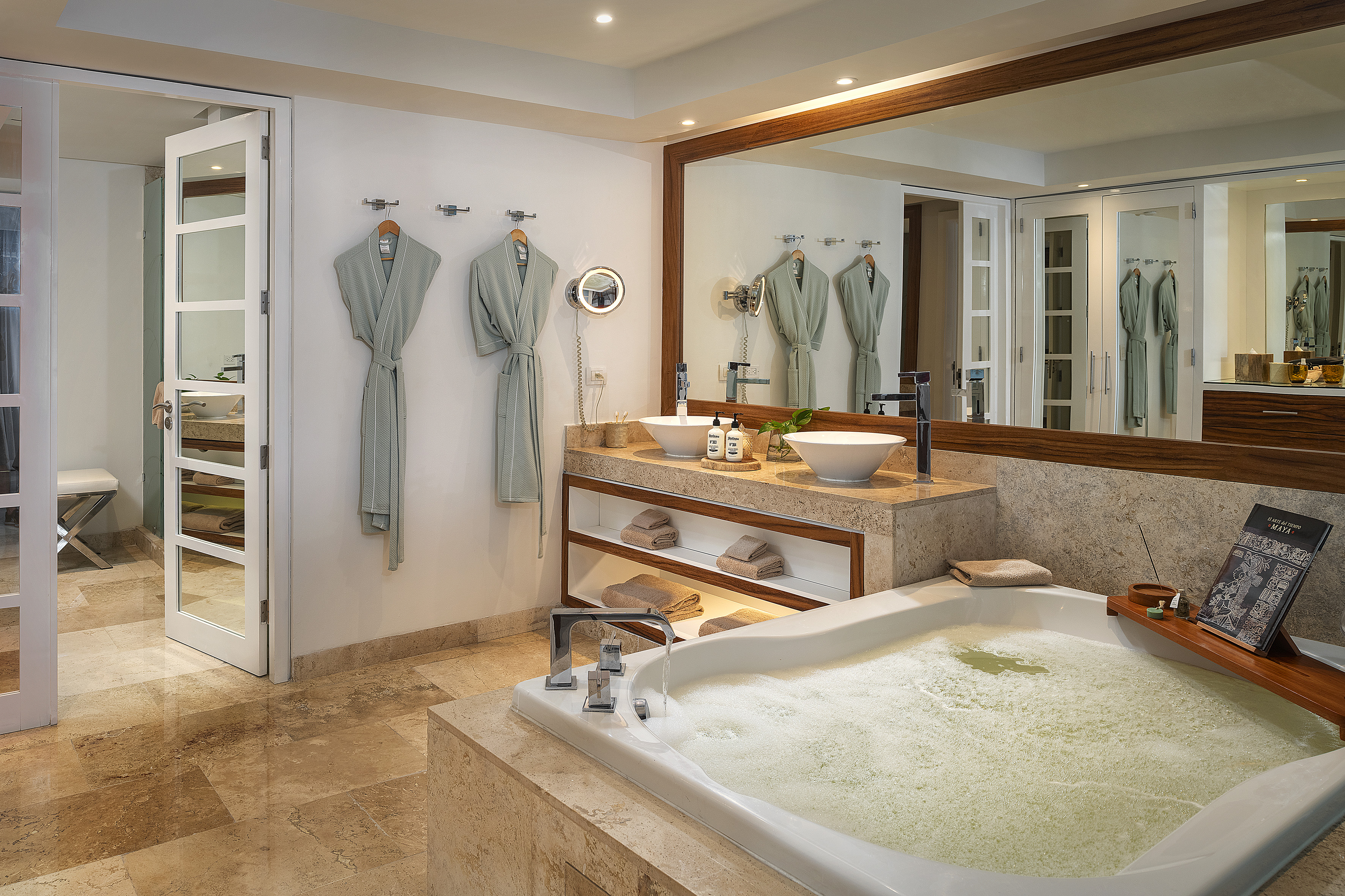 Luxury spa bathroom with large bubbling tub, double sinks, and robes.