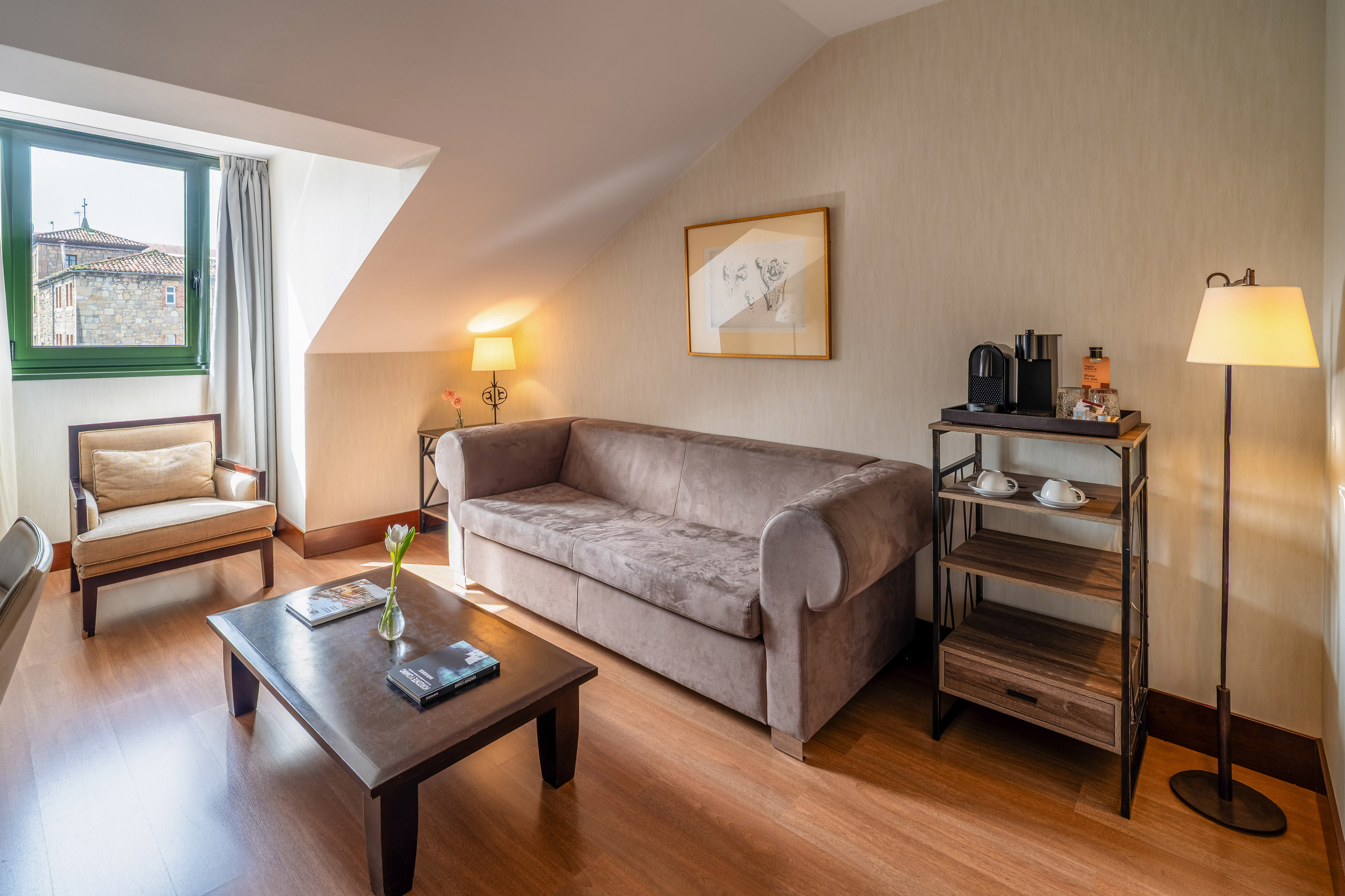 Cozy hotel suite living room with sofa, coffee station, and cityscape view.