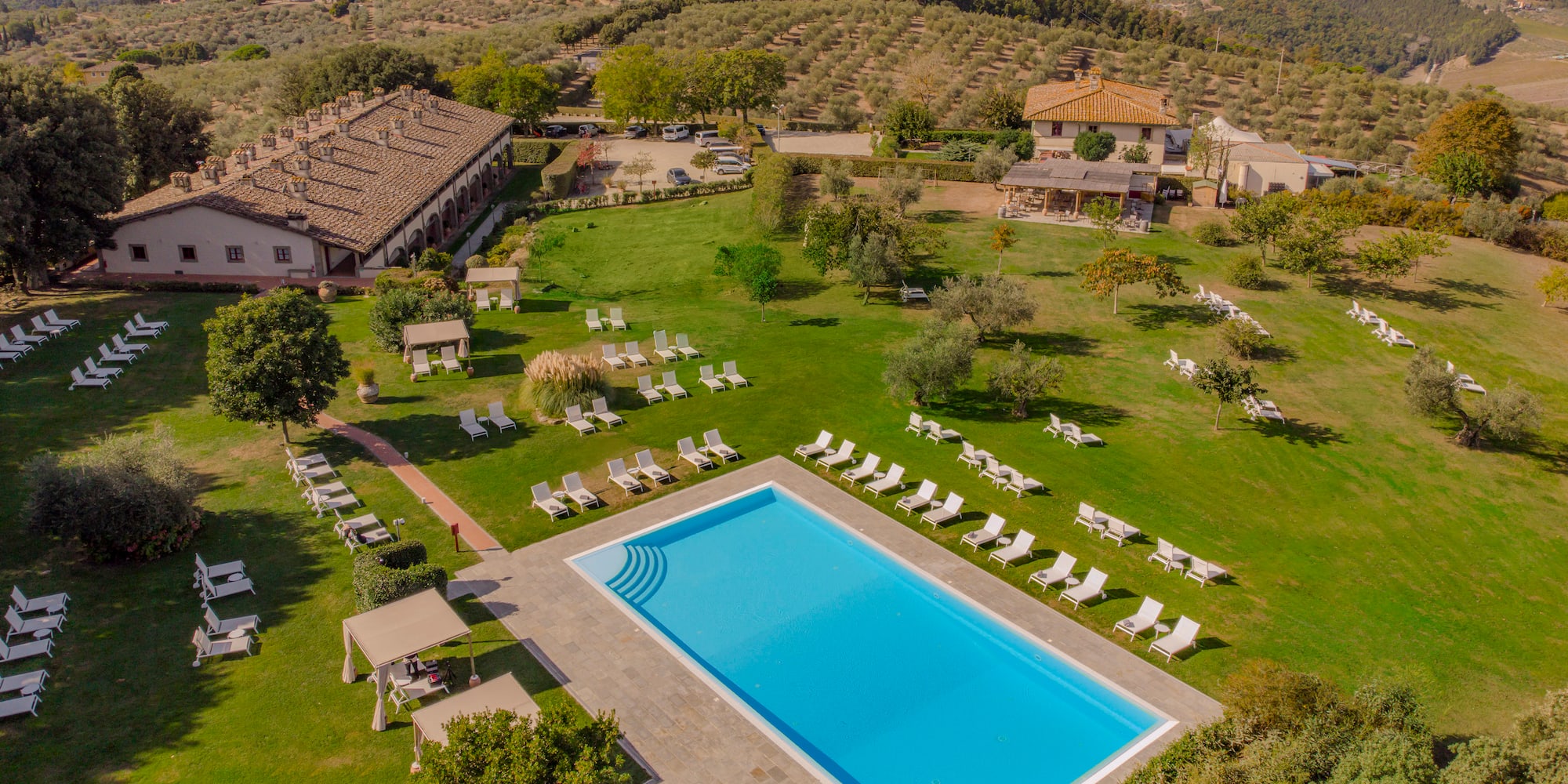 a pool in a grassy area with lawn chairs and trees