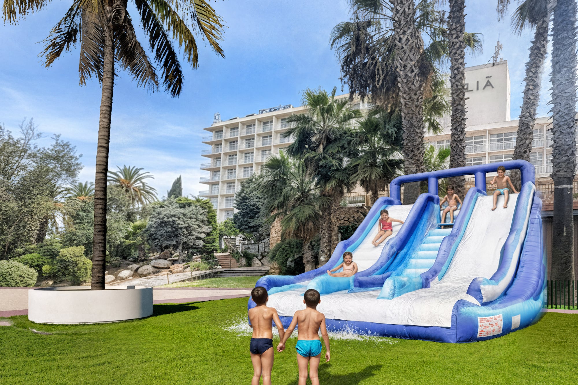 Kids playing on an inflatable water slide at a sunny hotel resort with palm trees.