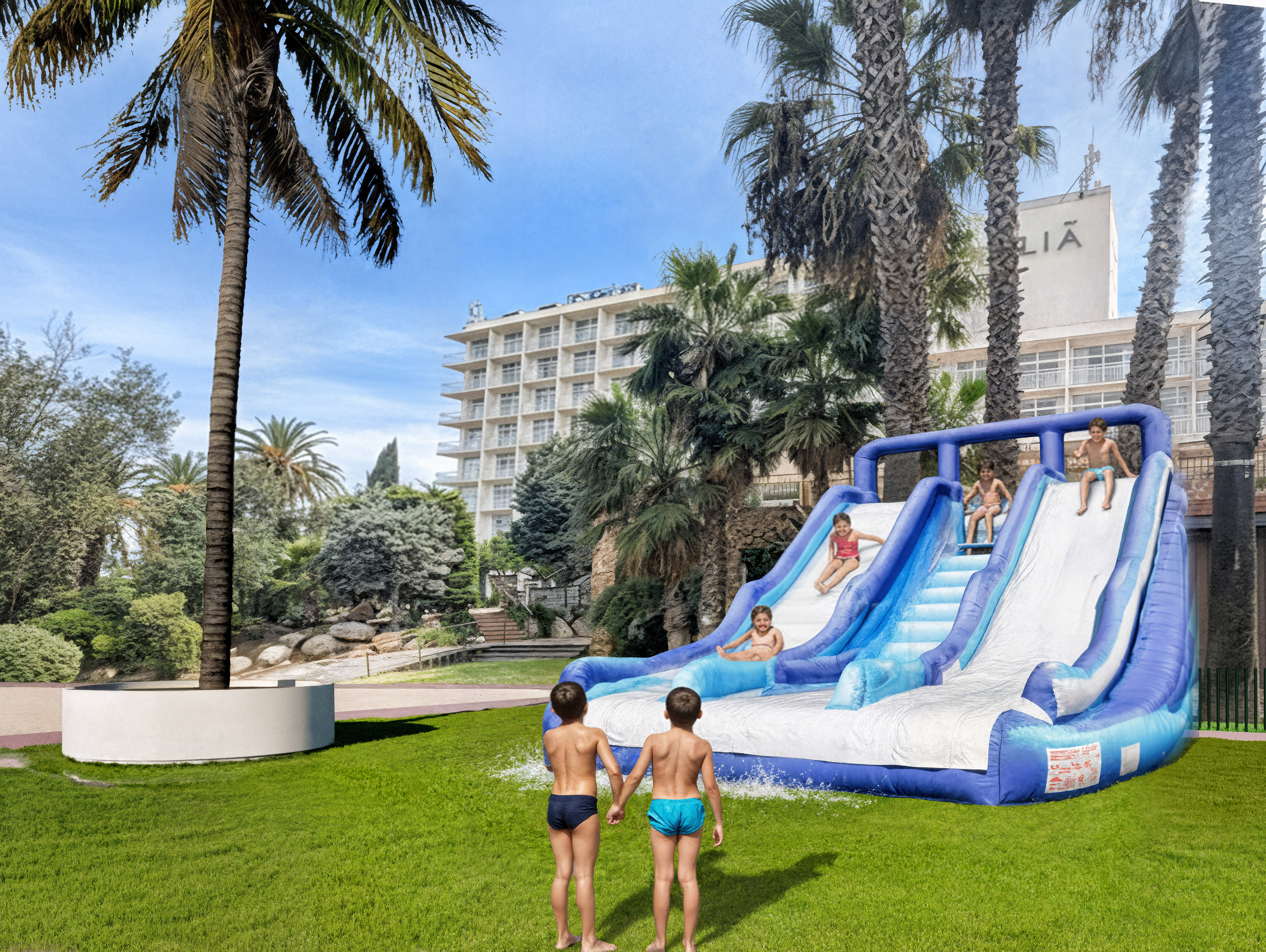 Kids playing on an inflatable water slide at a sunny hotel resort with palm trees.