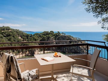 a table and chairs on a balcony overlooking a body of water