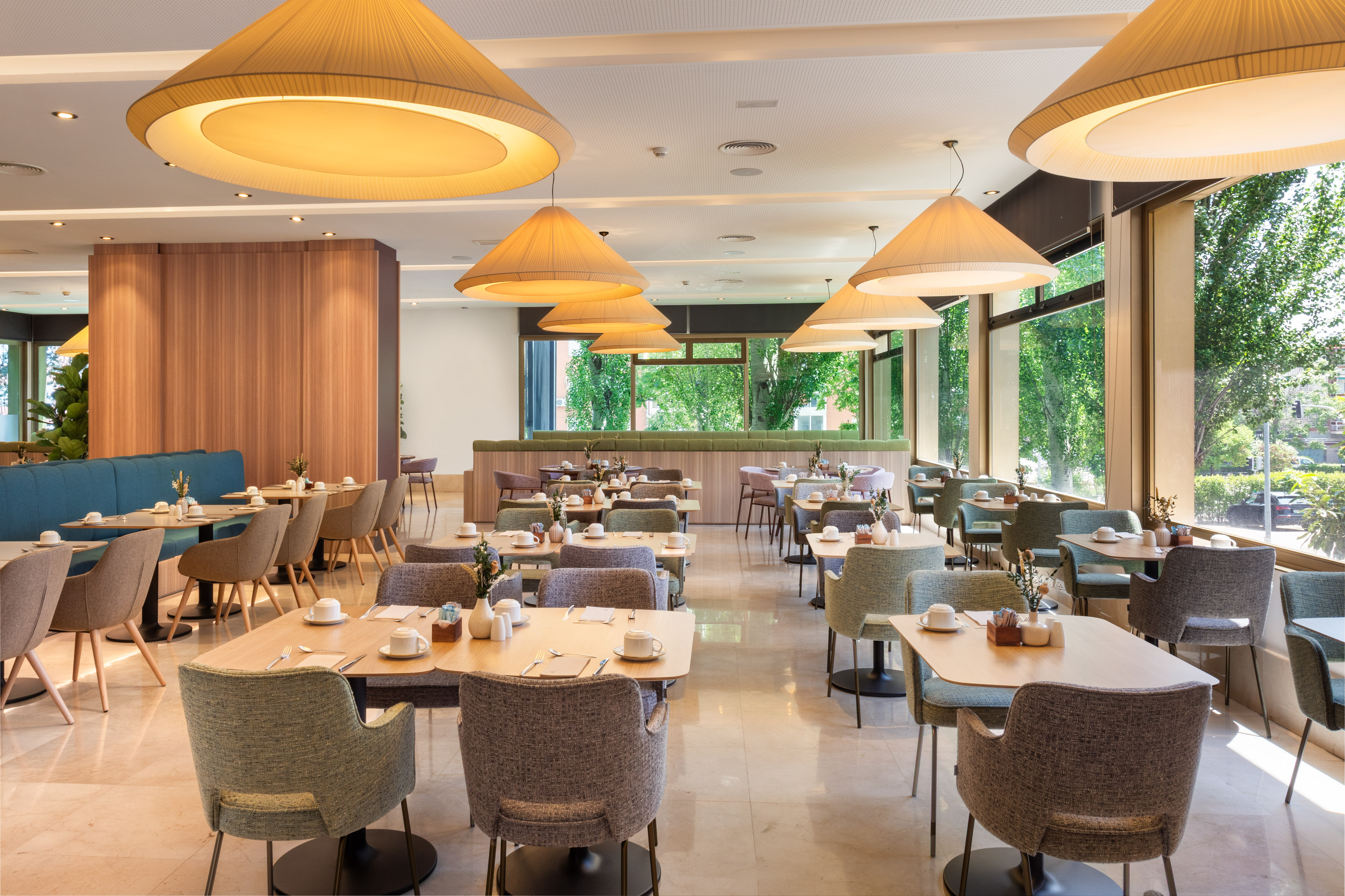 Contemporary hotel restaurant dining room with set tables and windows.