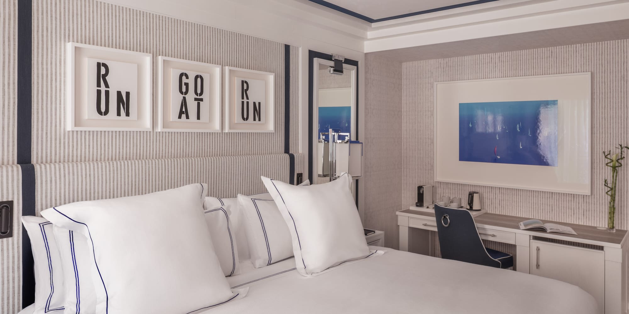 a bed with white pillows and a desk in a room