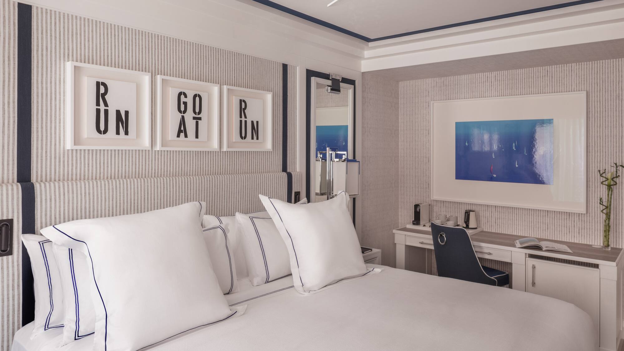 a bed with white pillows and a desk in a room