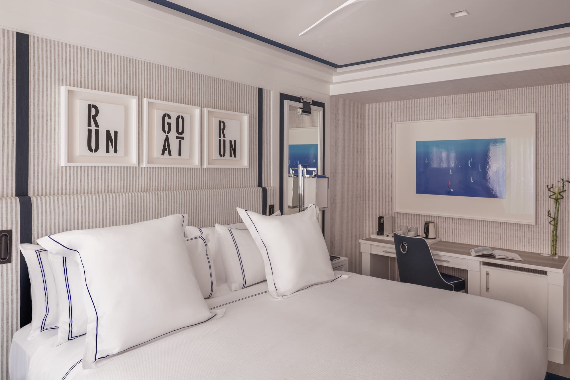 a bed with white pillows and a desk in a room