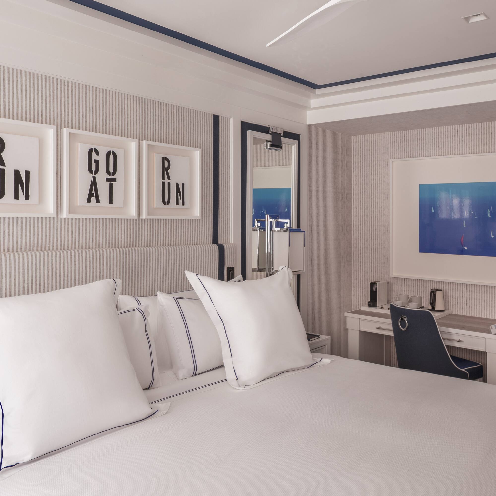 a bed with white pillows and a desk in a room