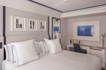 a bed with white pillows and a desk in a room