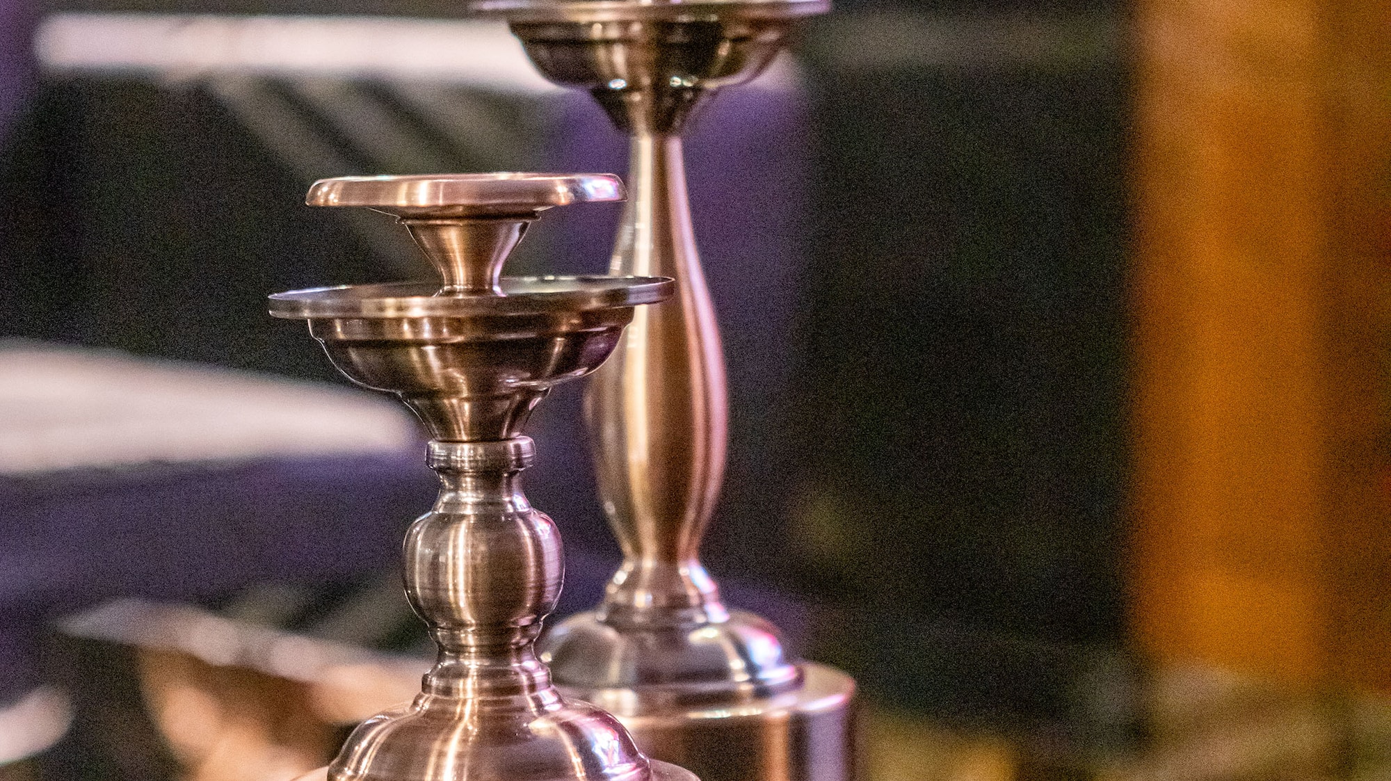 a pair of metal candlesticks on a glass table