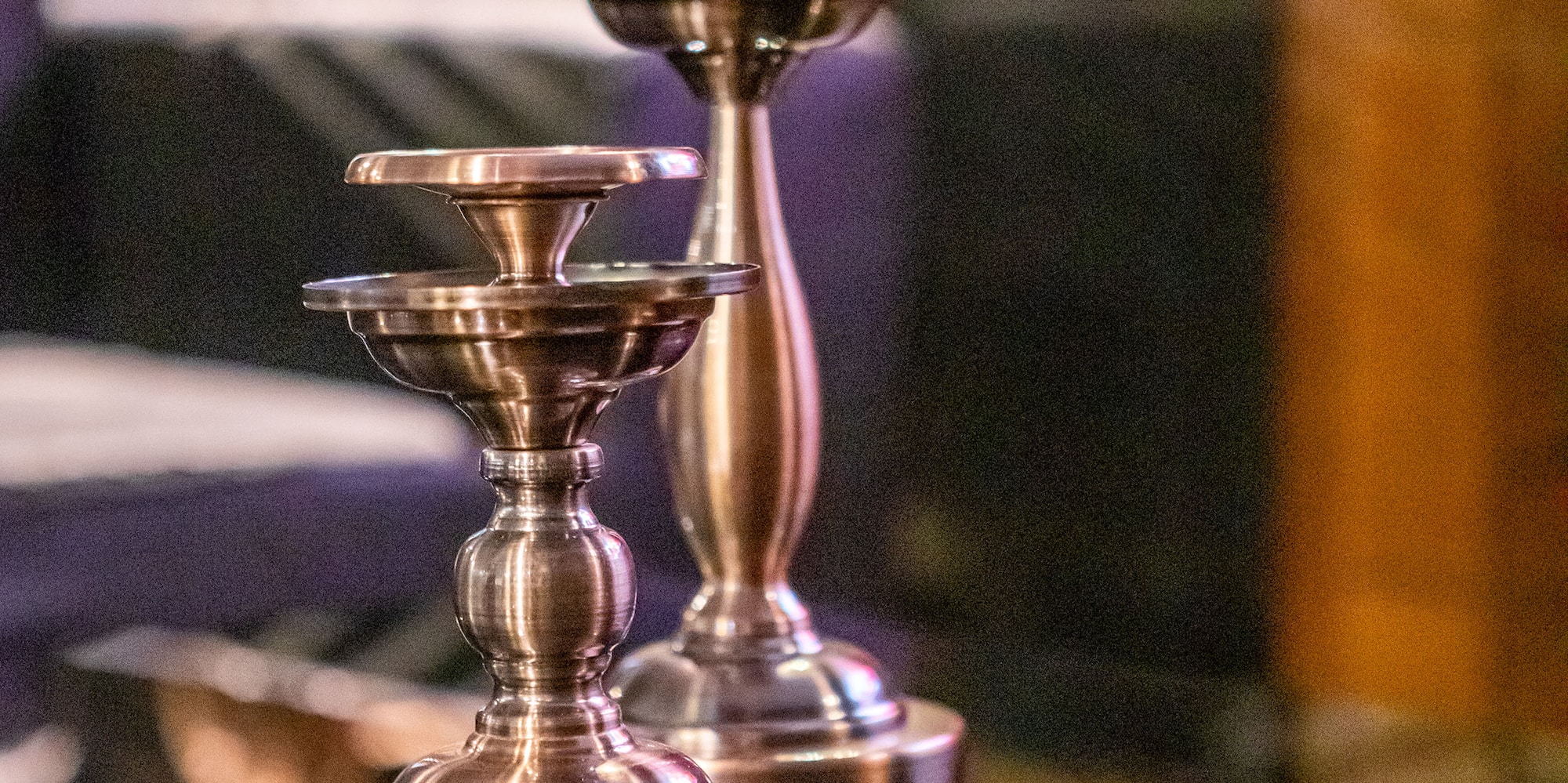 a pair of metal candlesticks on a glass table
