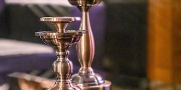 a pair of metal candlesticks on a glass table