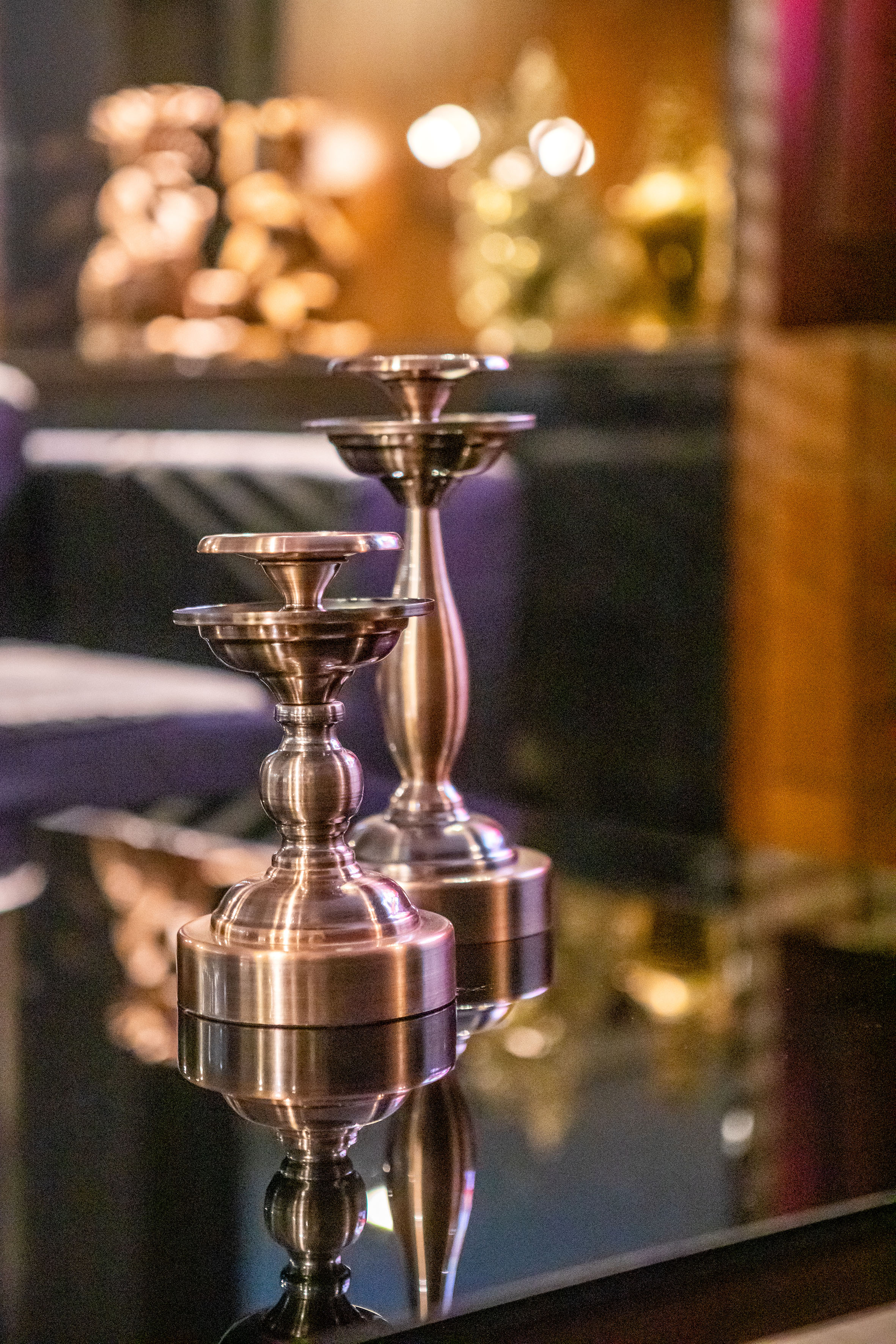 a pair of metal candlesticks on a glass table