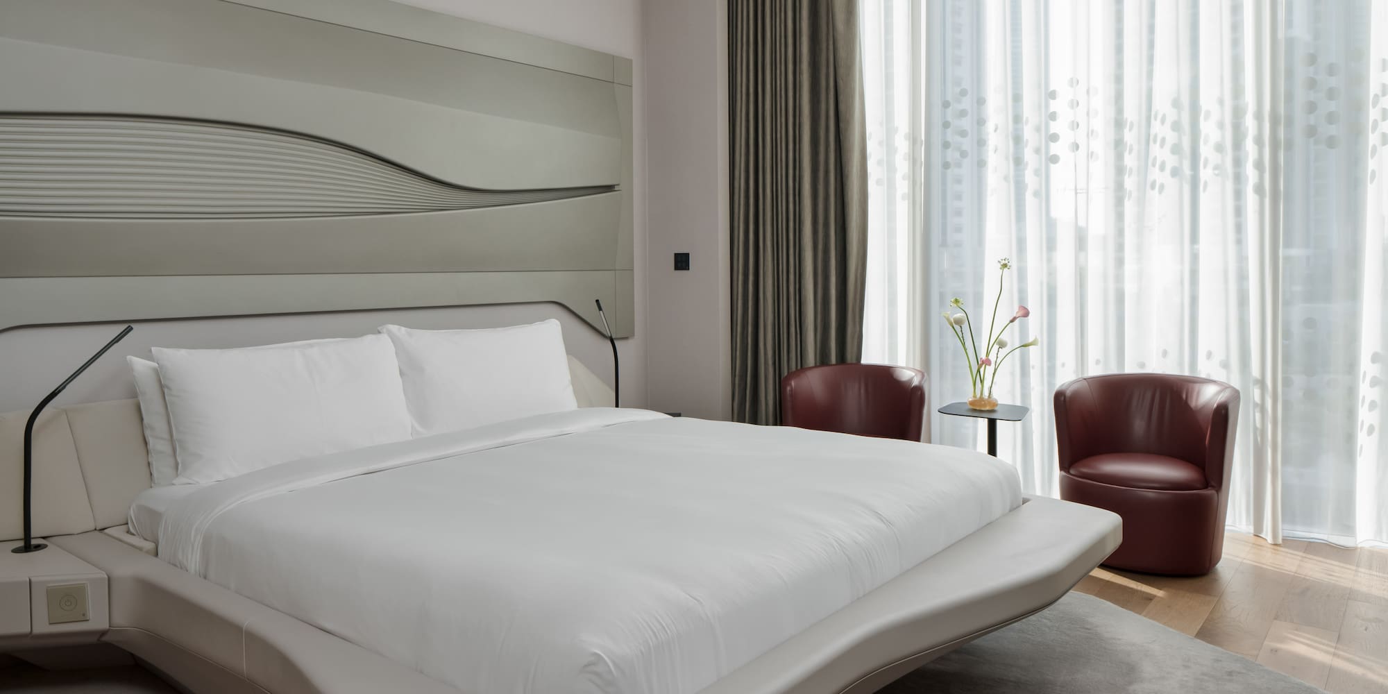 a bed with a headboard and chairs in a room