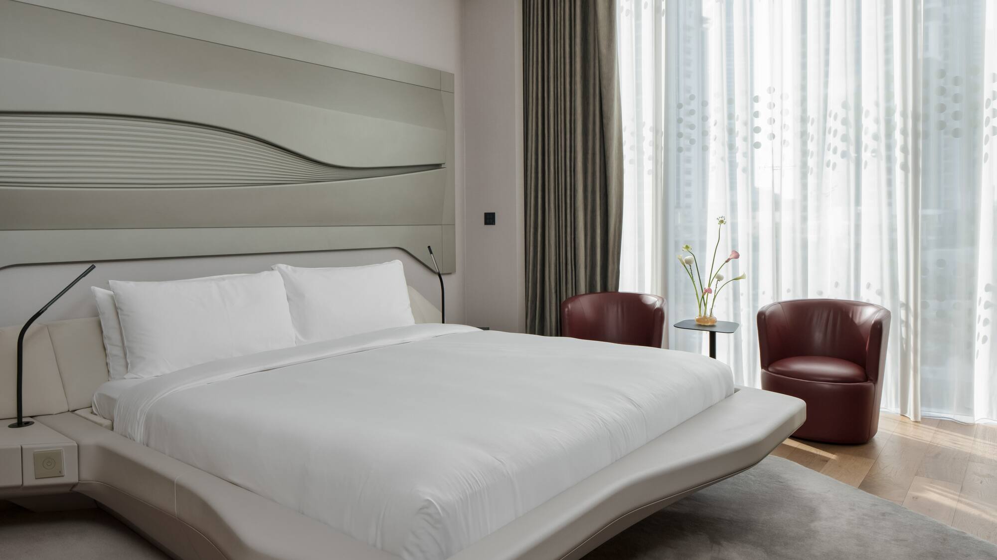 a bed with a headboard and chairs in a room