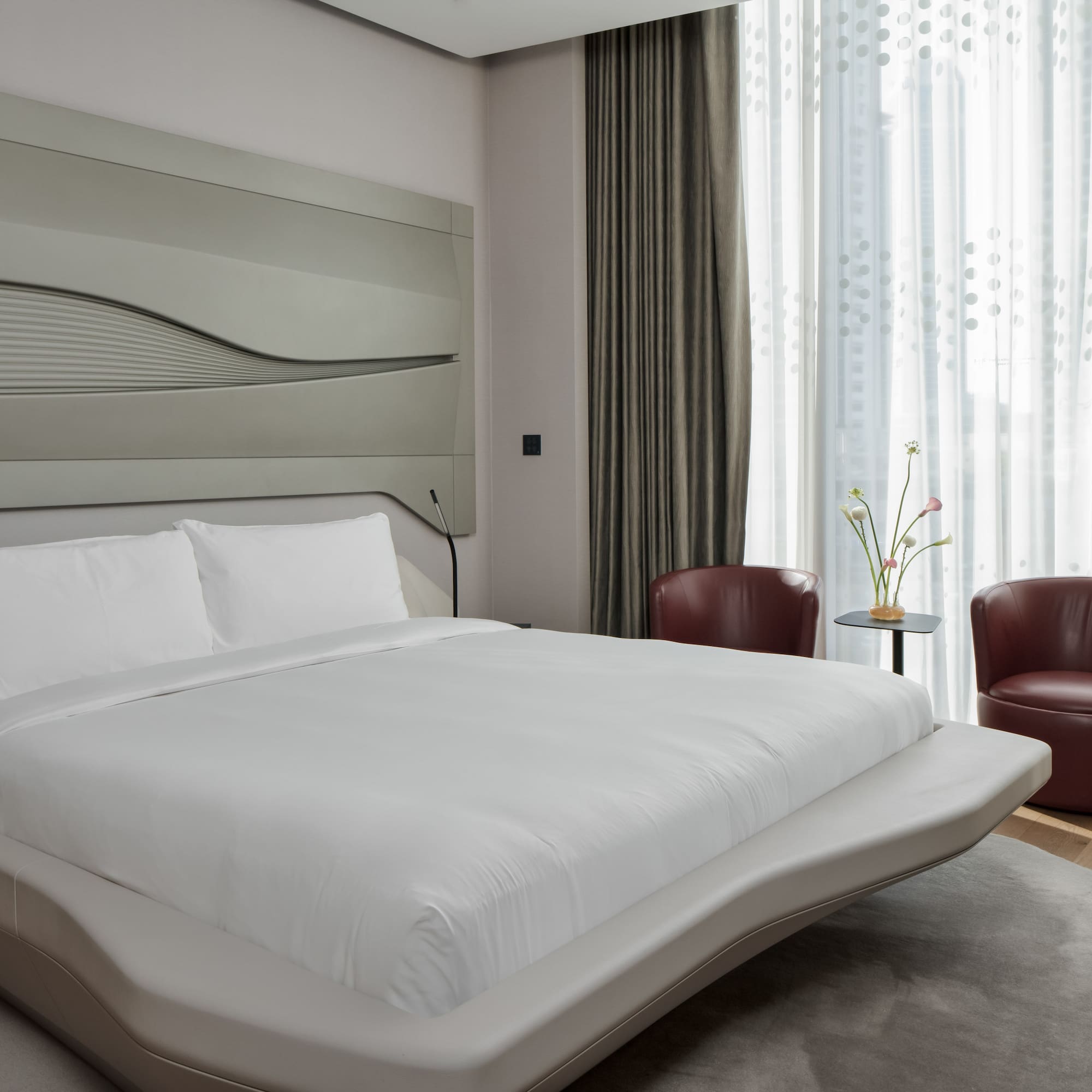 a bed with a headboard and chairs in a room