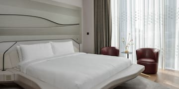 a bed with a headboard and chairs in a room