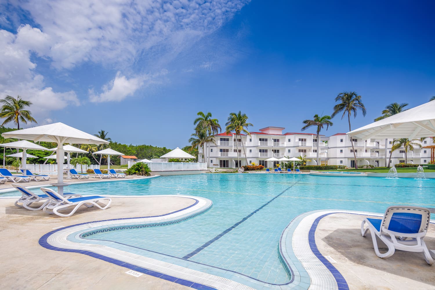 a swimming pool with white buildings and palm trees
