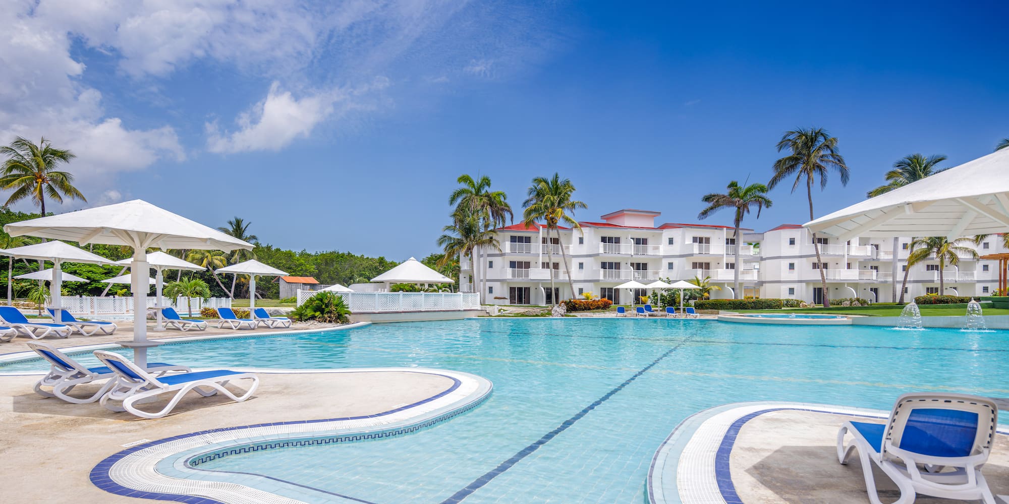 a swimming pool with white buildings and palm trees