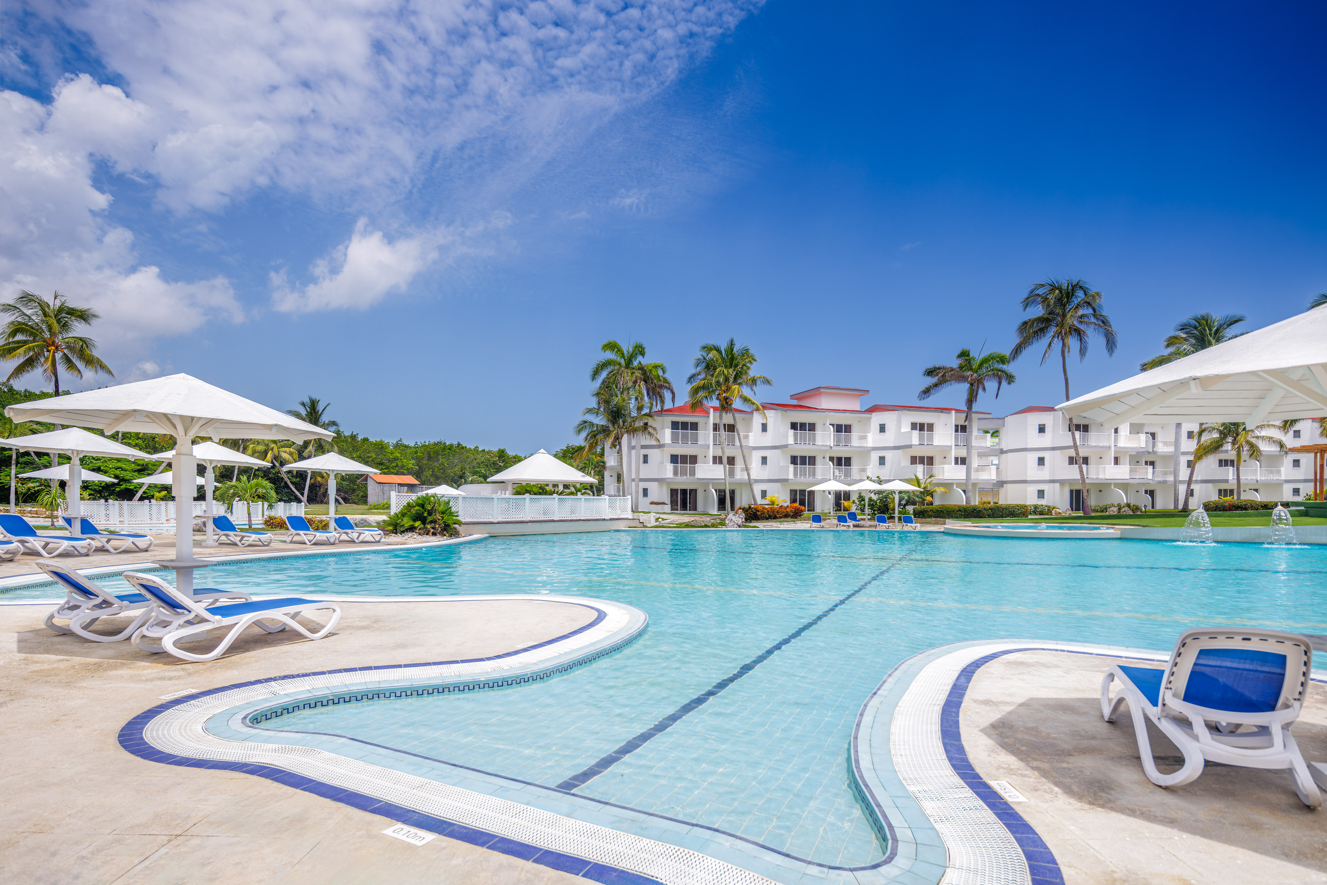 a swimming pool with white buildings and palm trees