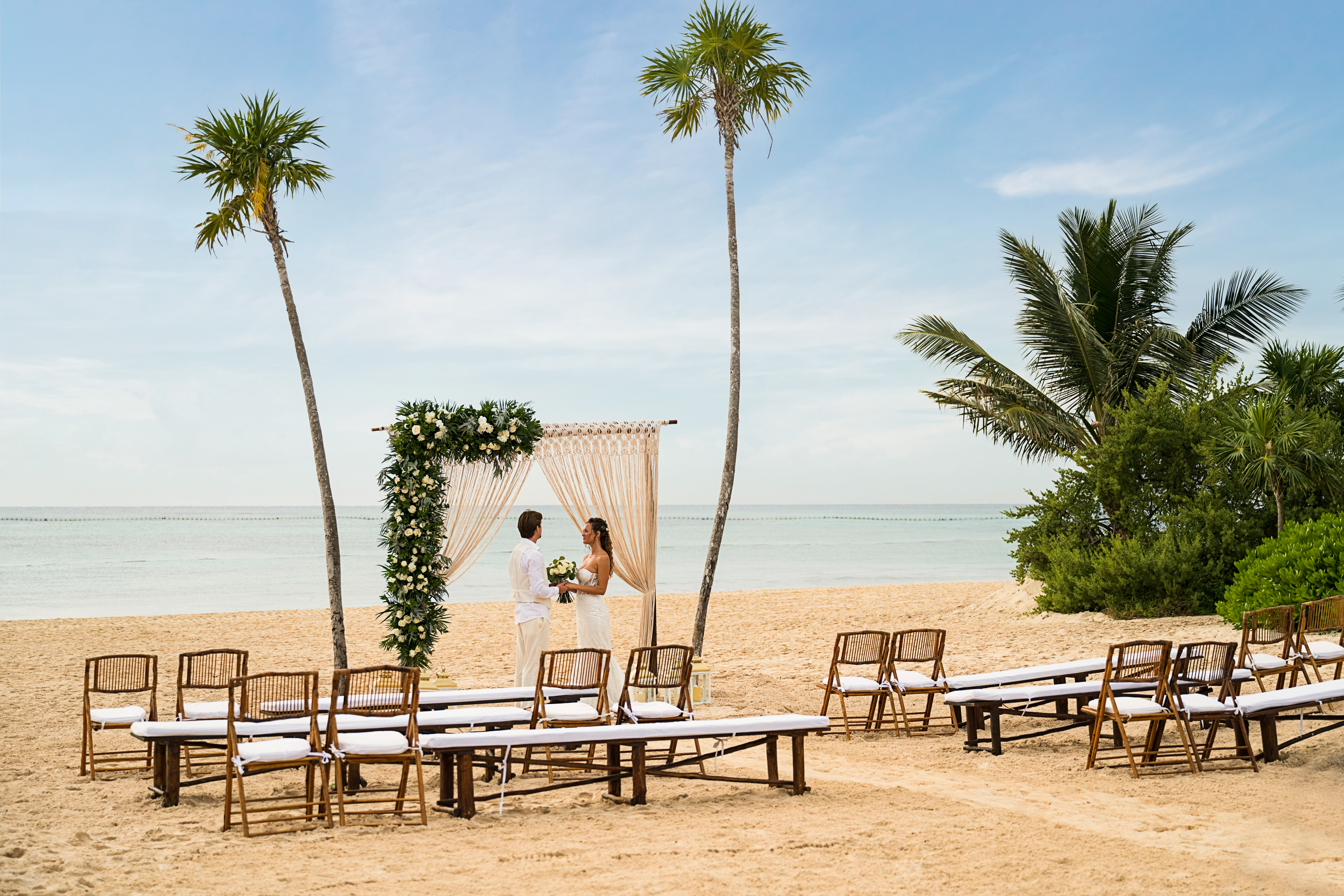 a man and woman under a wedding arch on a beach