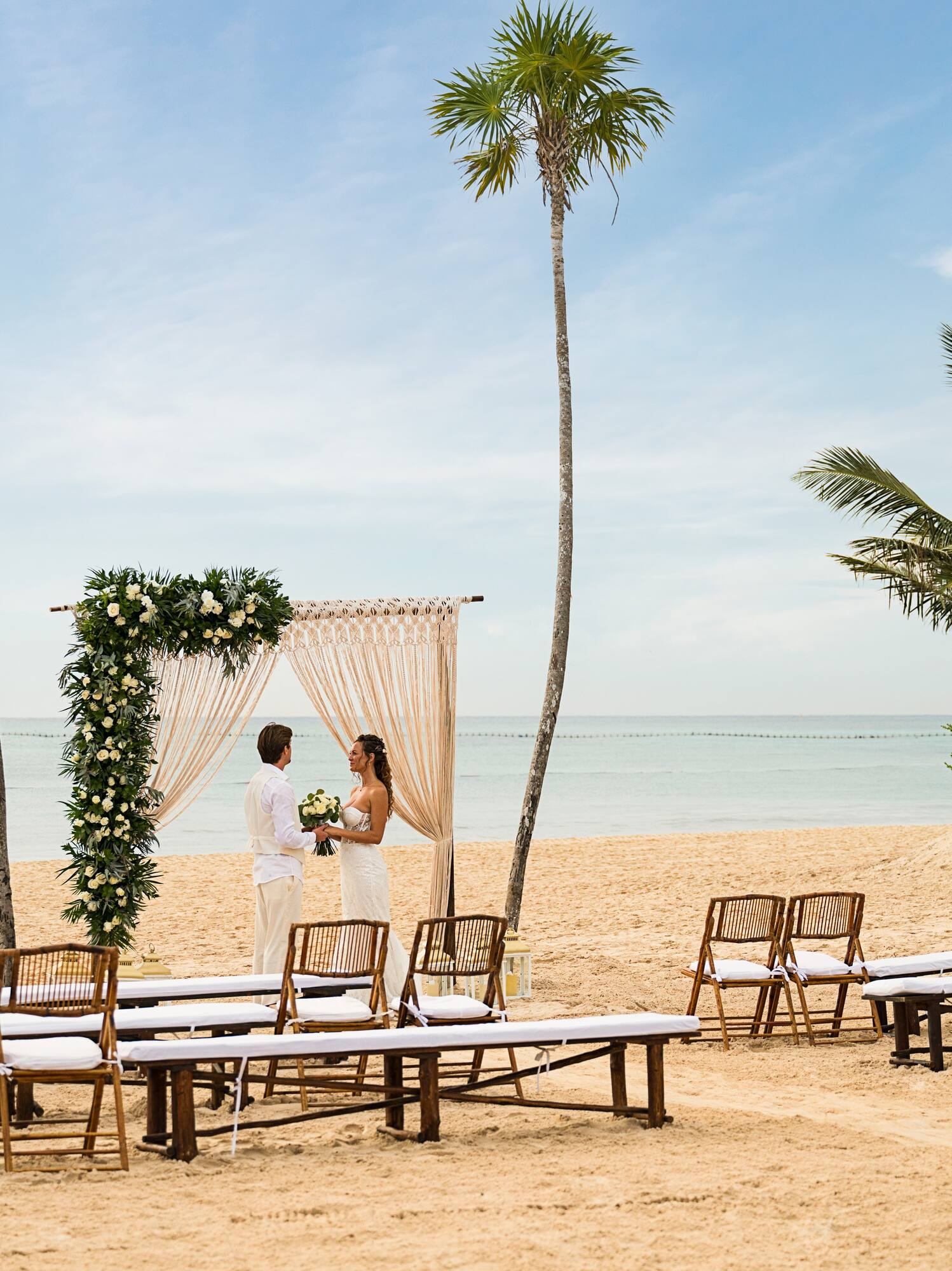 a man and woman under a wedding arch on a beach