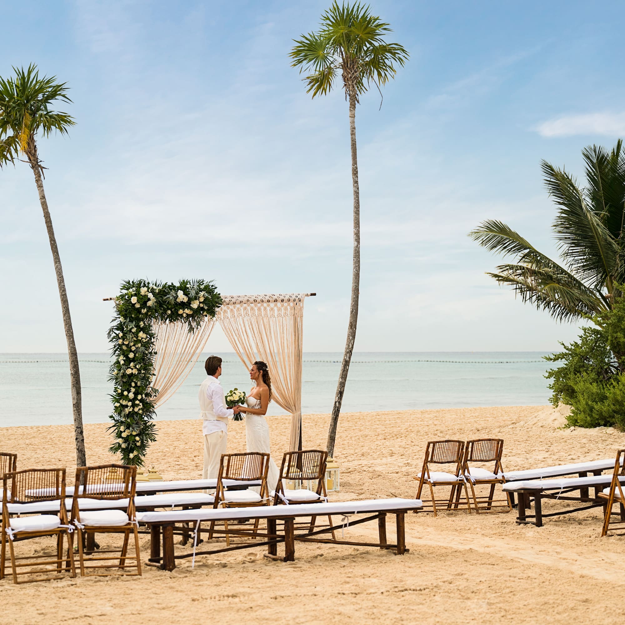 a man and woman under a wedding arch on a beach