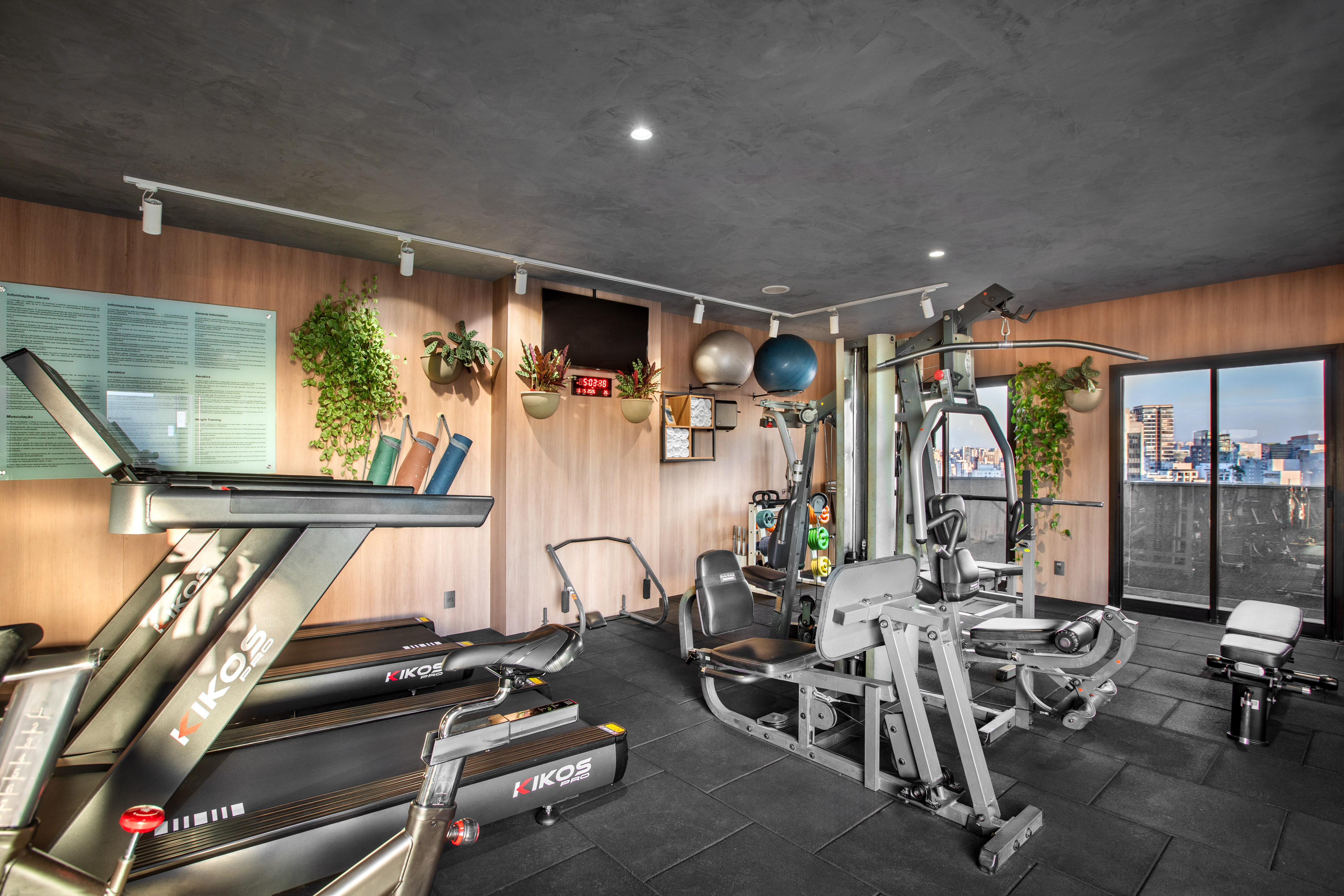 Spacious gym with modern equipment, treadmills, weights, and city skyline view.
