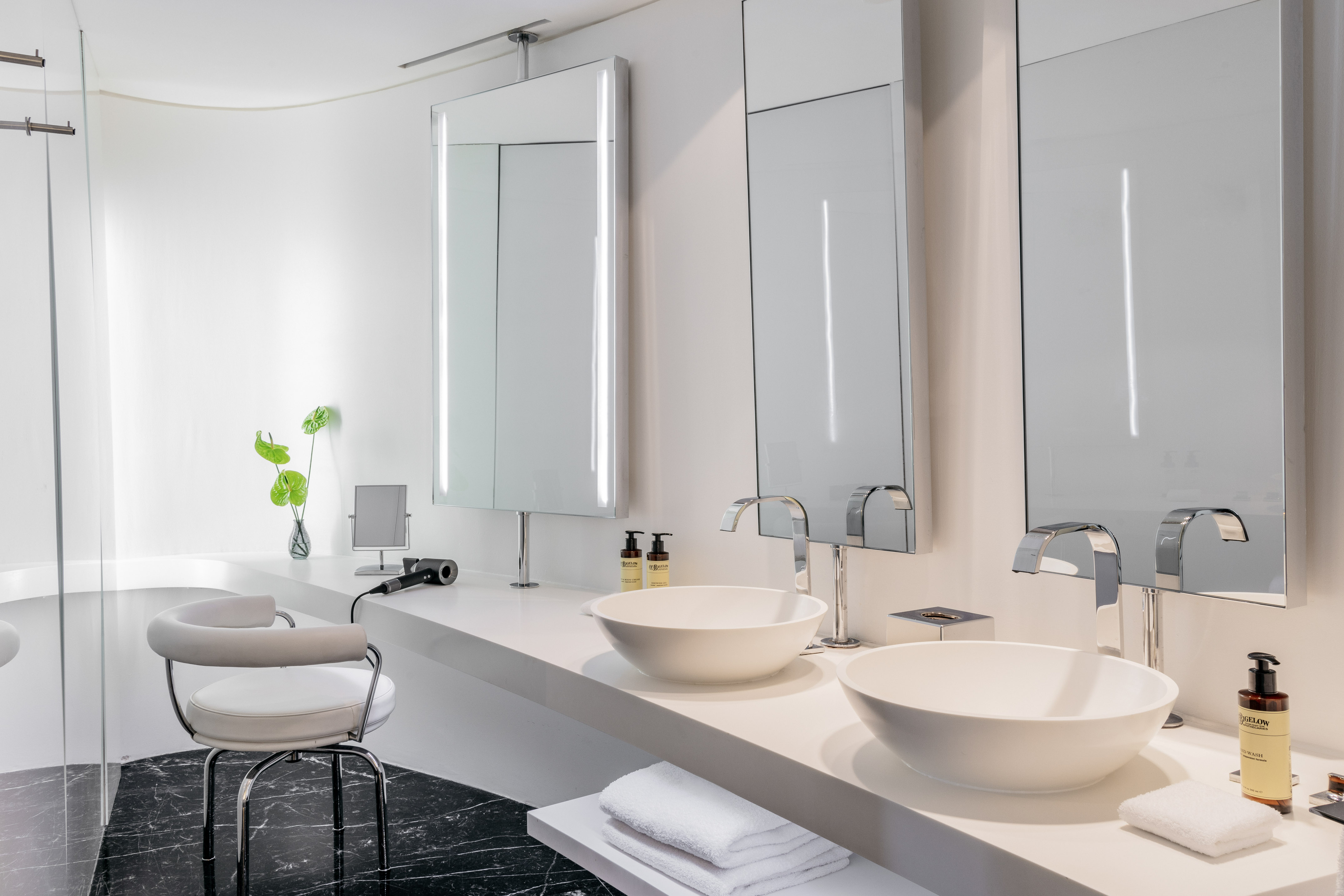 Modern bathroom with double vanity, LED mirrors, and black marble floor.