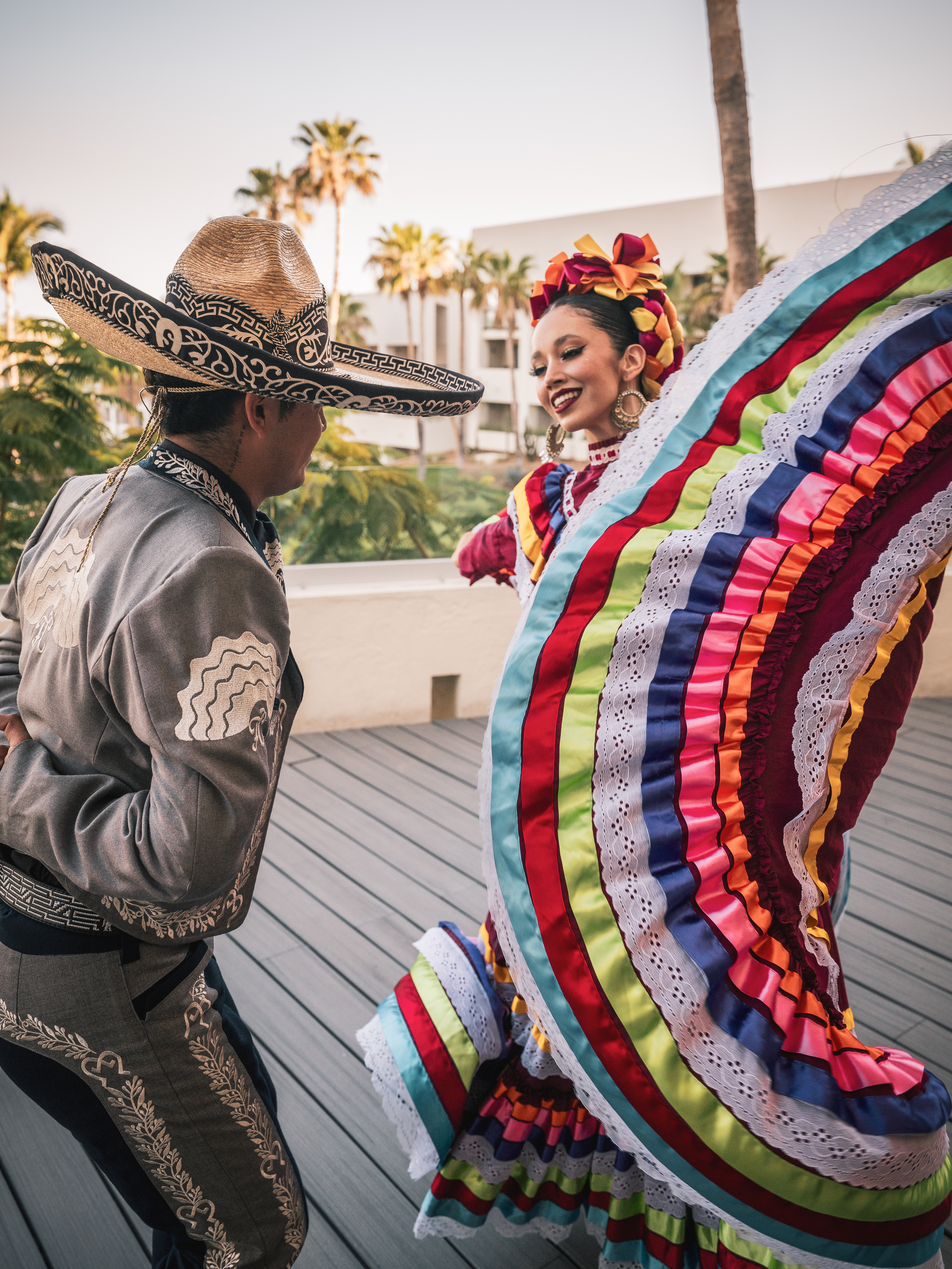 Mexican folkloric dancers in vibrant traditional costumes dancing outdoors.