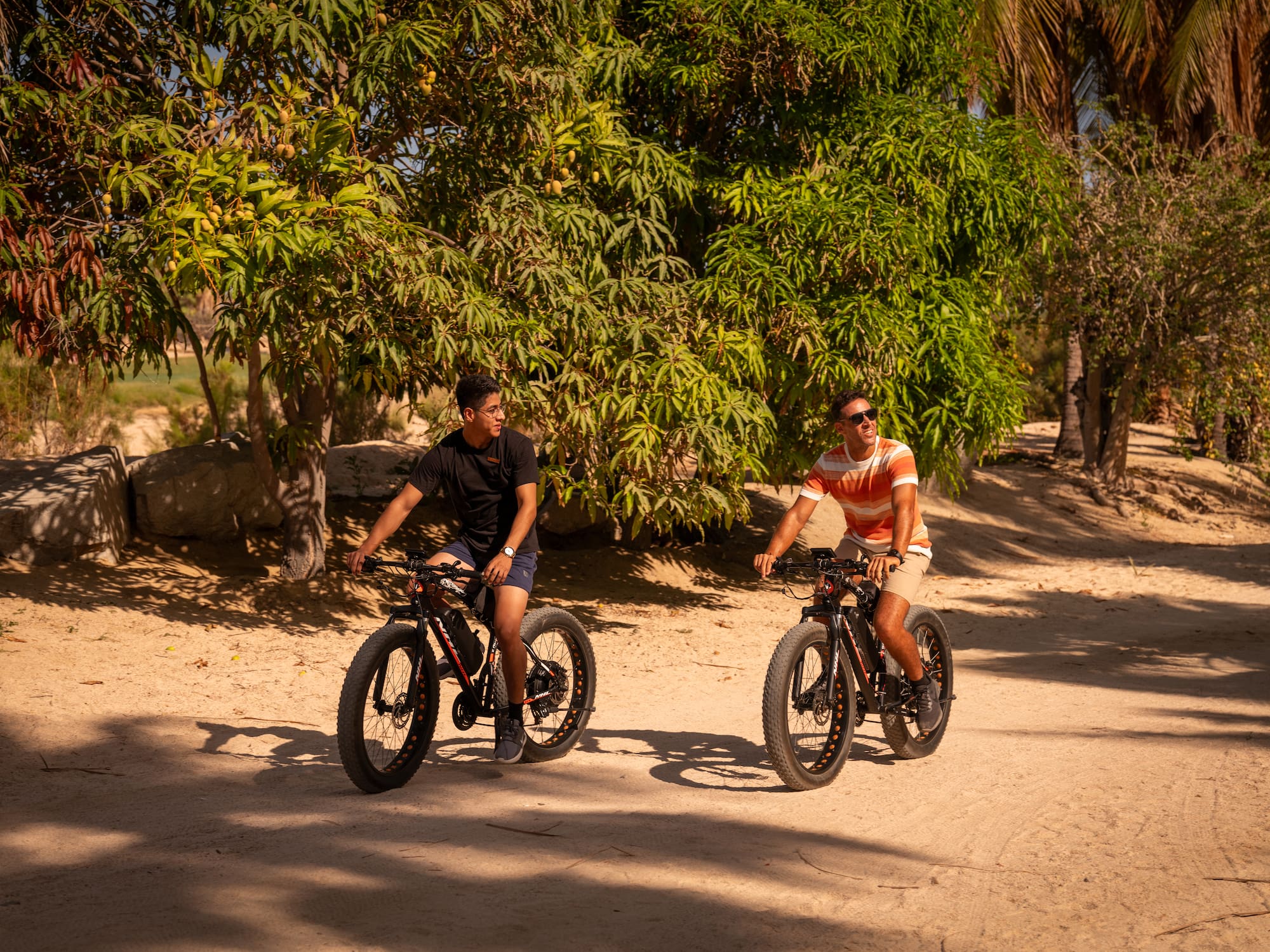 two men riding bikes on a dirt road