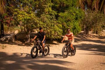 two men riding bikes on a dirt road
