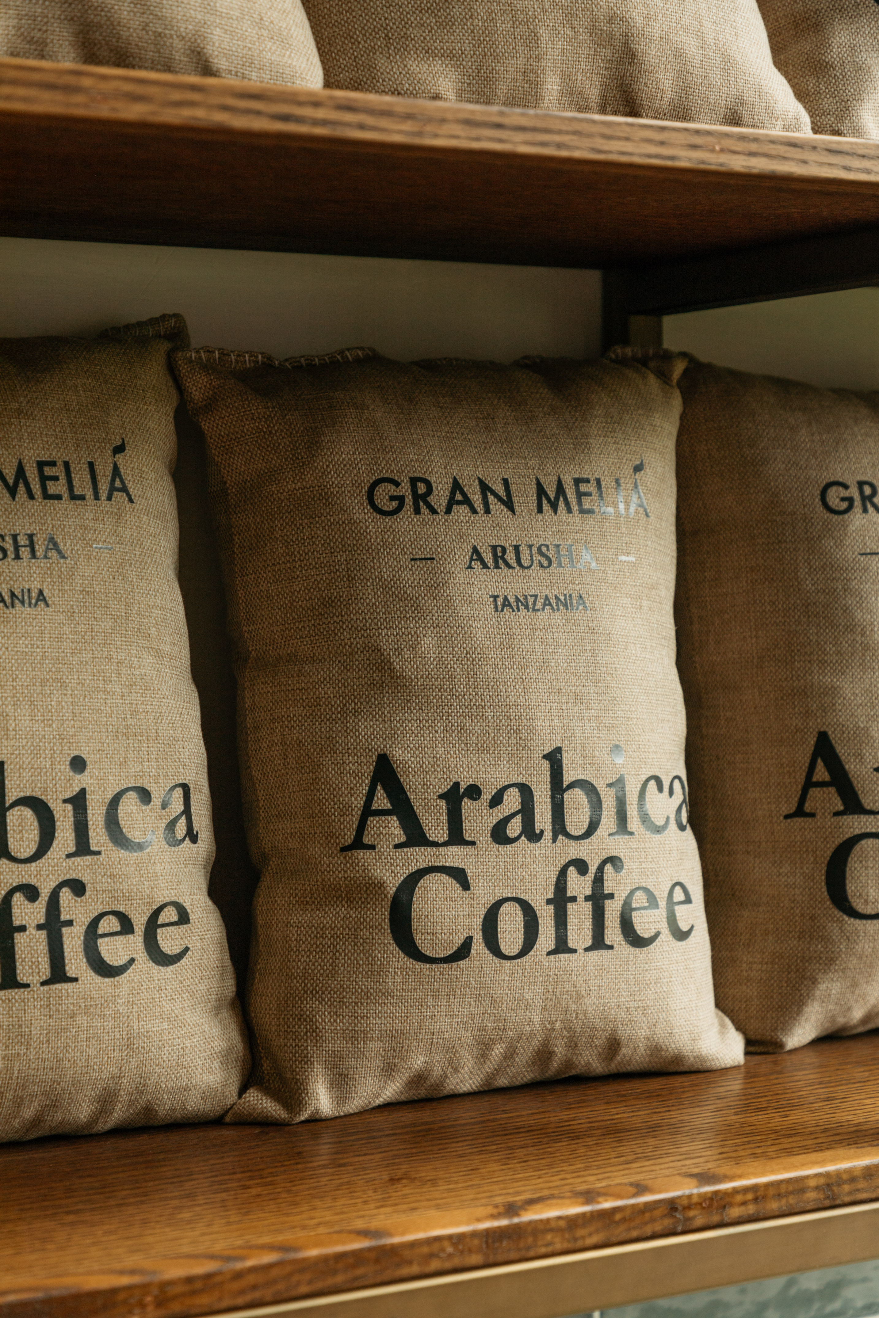 Gran Meliá Arusha Arabica coffee bags on wooden shelf.