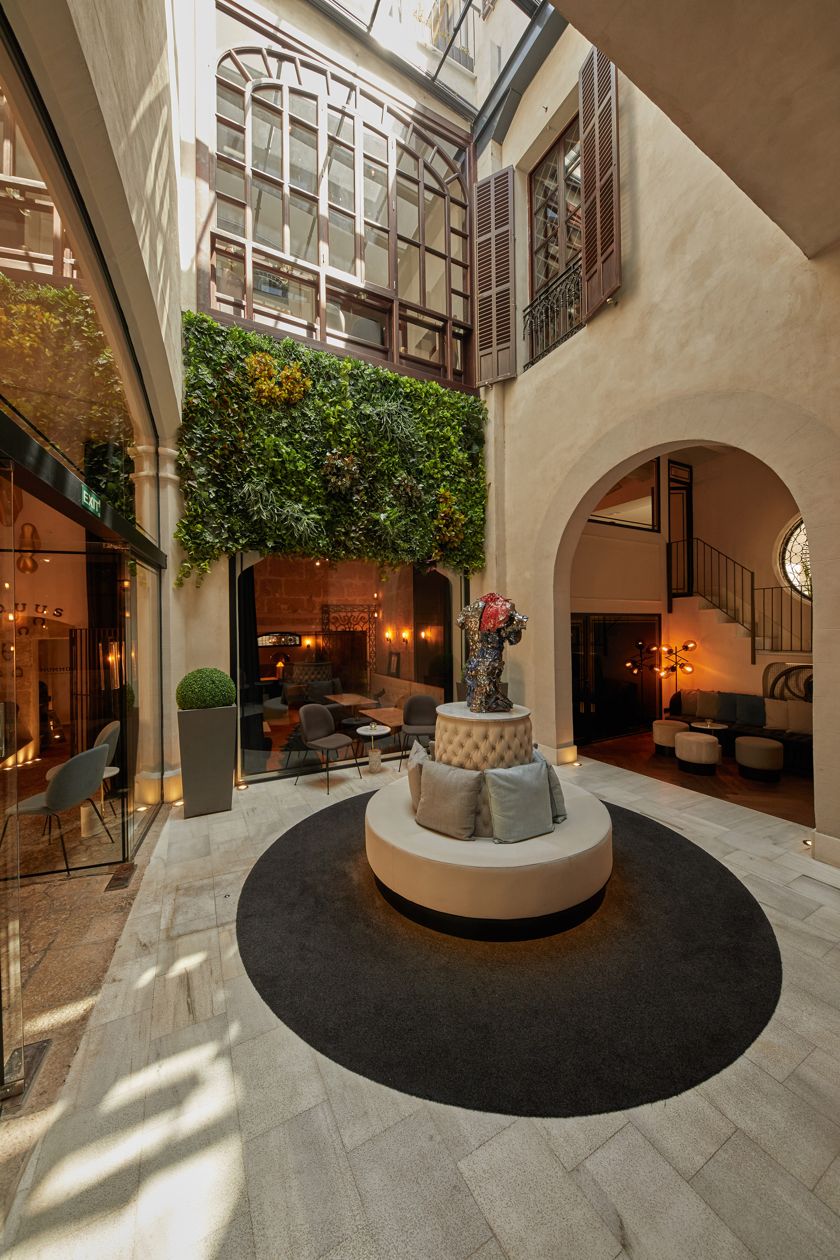 Hotel atrium featuring a vertical garden, circular seating, and elegant archways.
