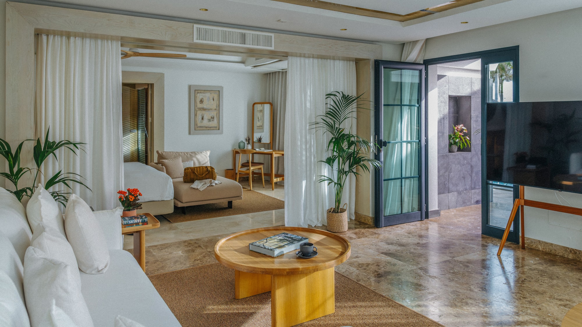 Modern luxury suite: open living area, white sofa, wood table, plant decor.