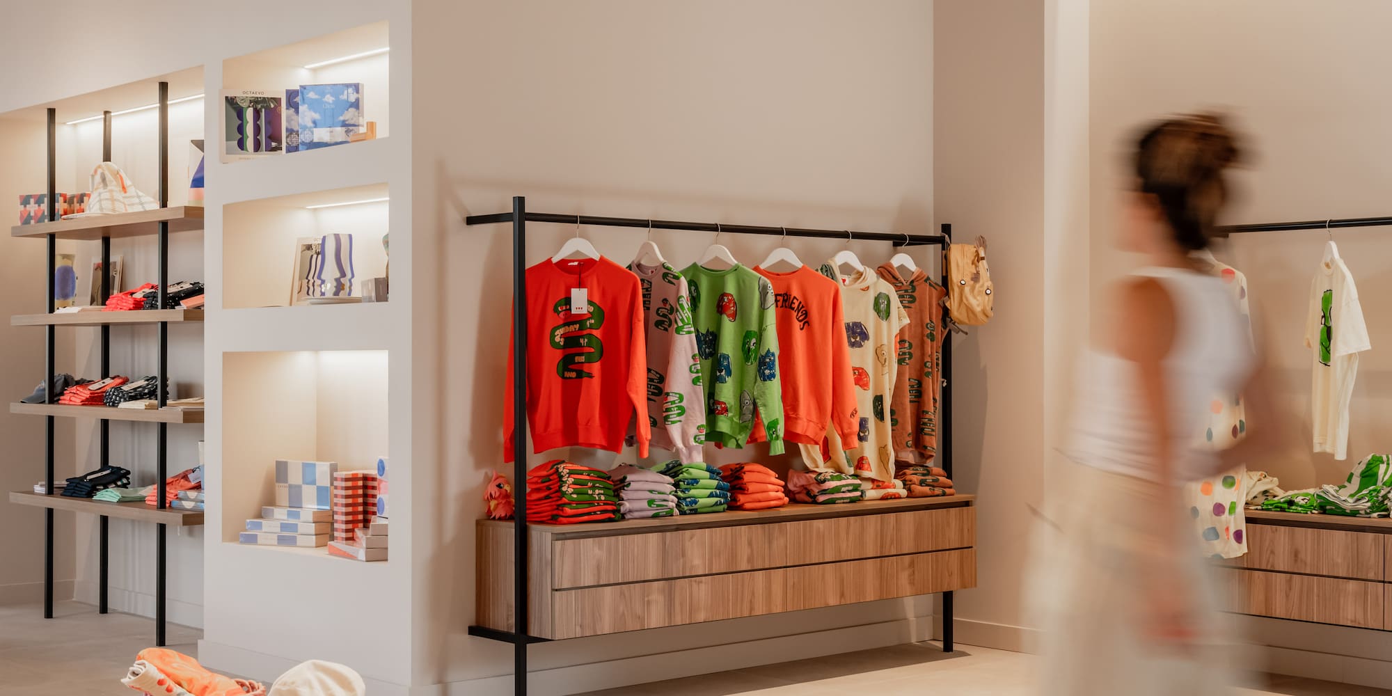 a woman walking past a store with clothes on swingers