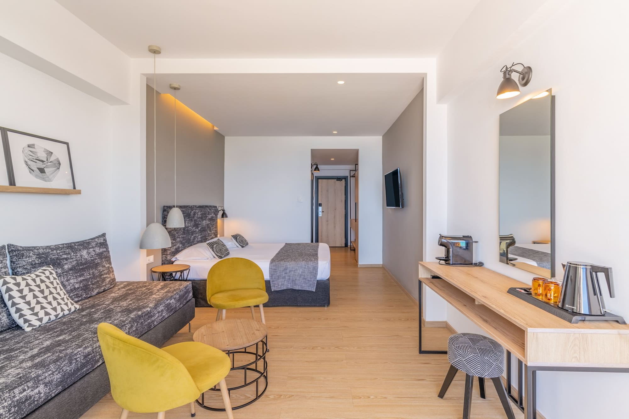 Contemporary hotel suite with sofa, bed, and desk.