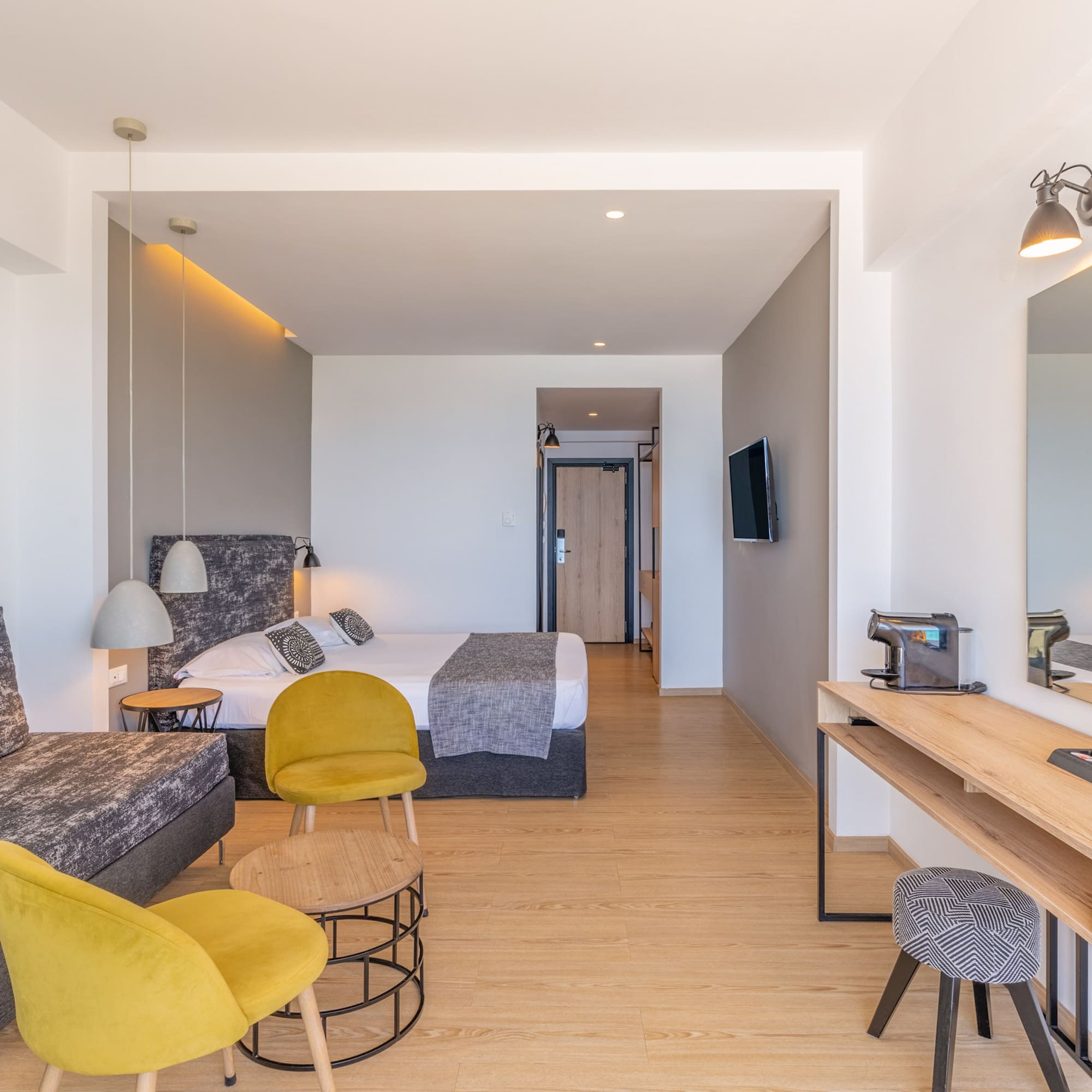 Contemporary hotel suite with sofa, bed, and desk.