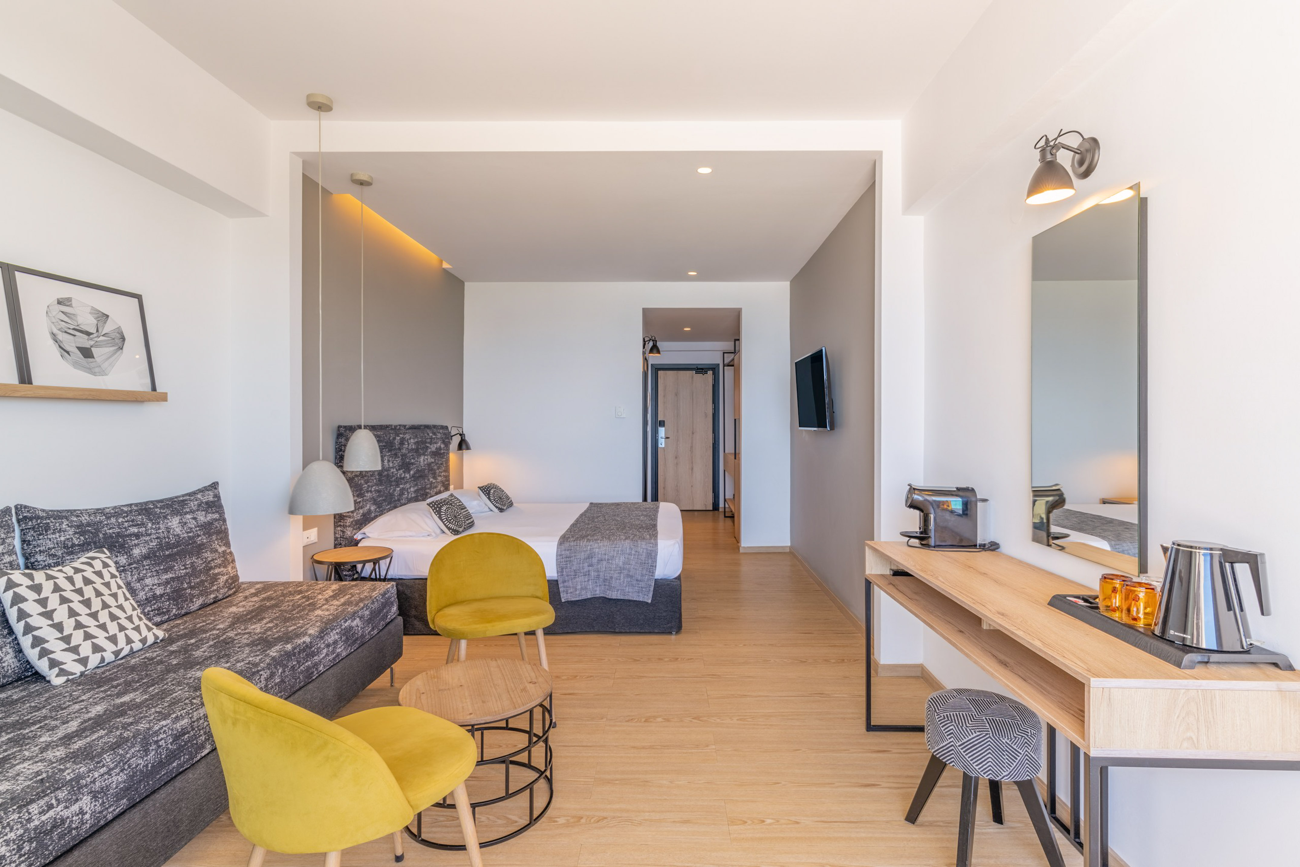 Contemporary hotel suite with sofa, bed, and desk.