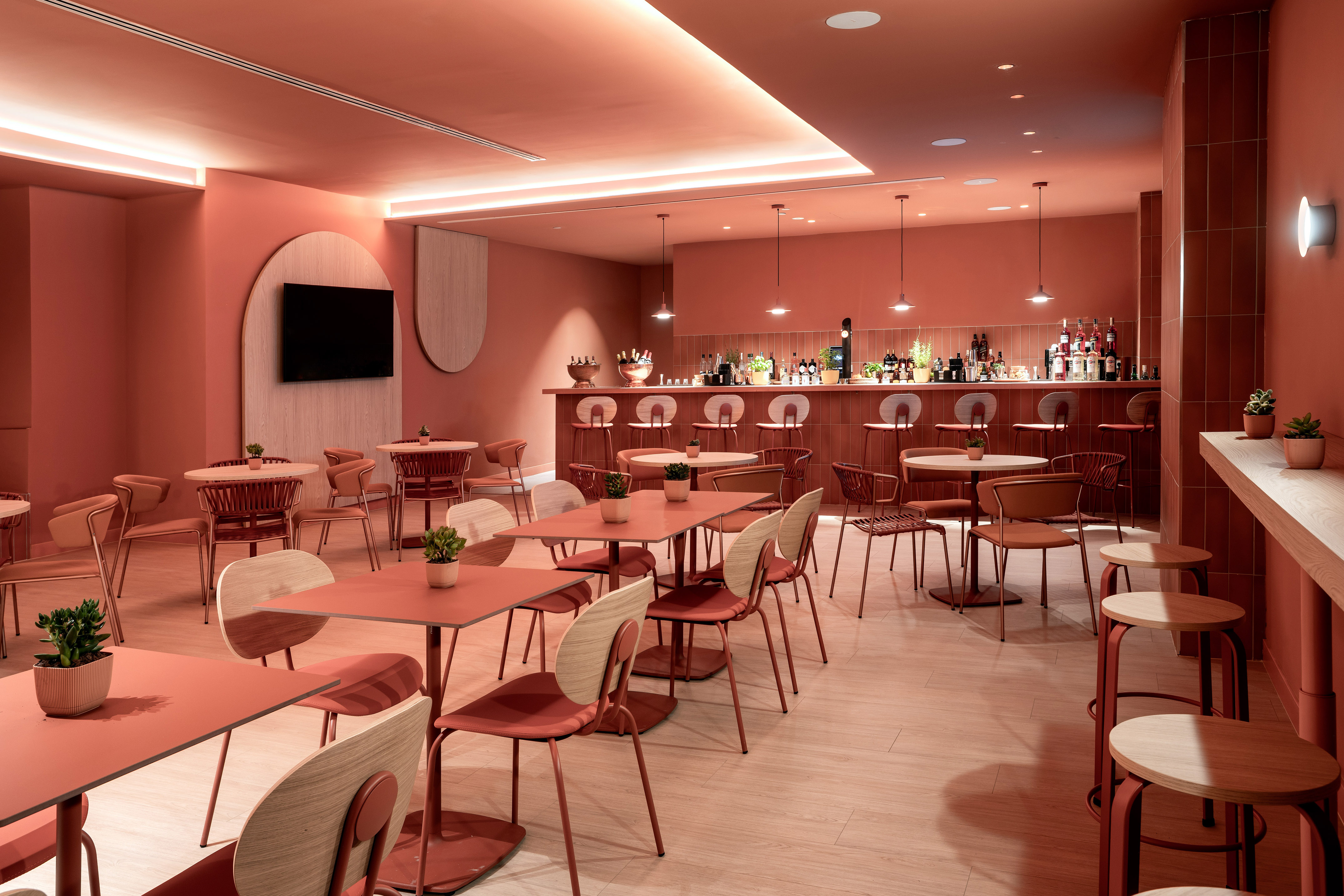 Modern coral and wood restaurant bar with dining tables and chairs.