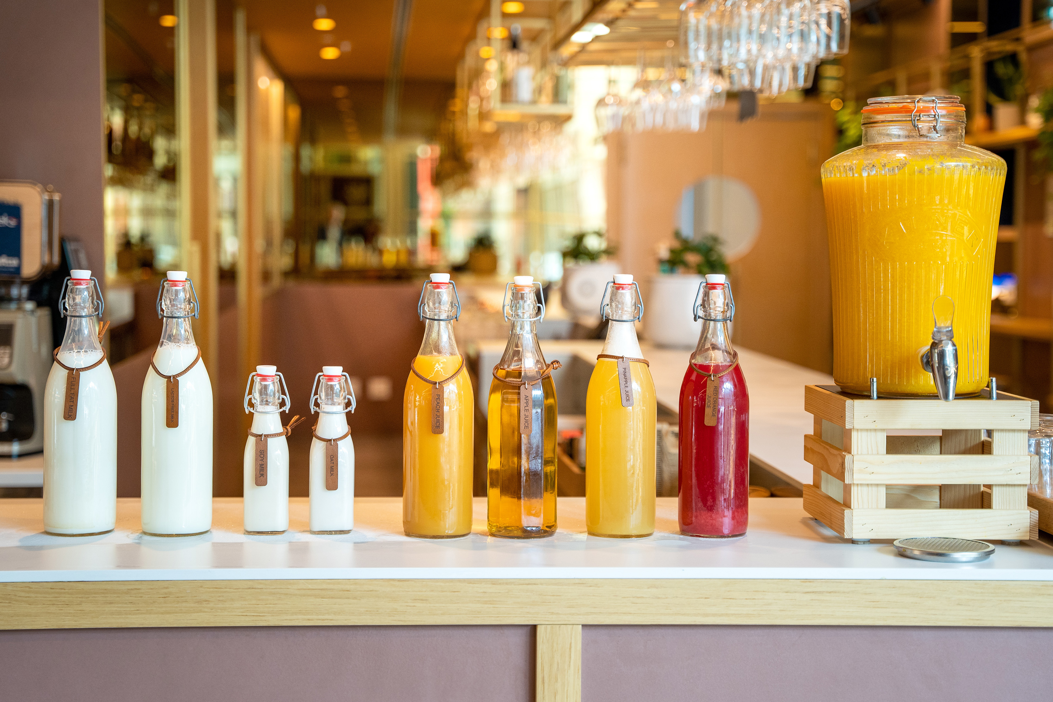 Breakfast buffet with bottled milks, fresh juices, and orange juice dispenser.