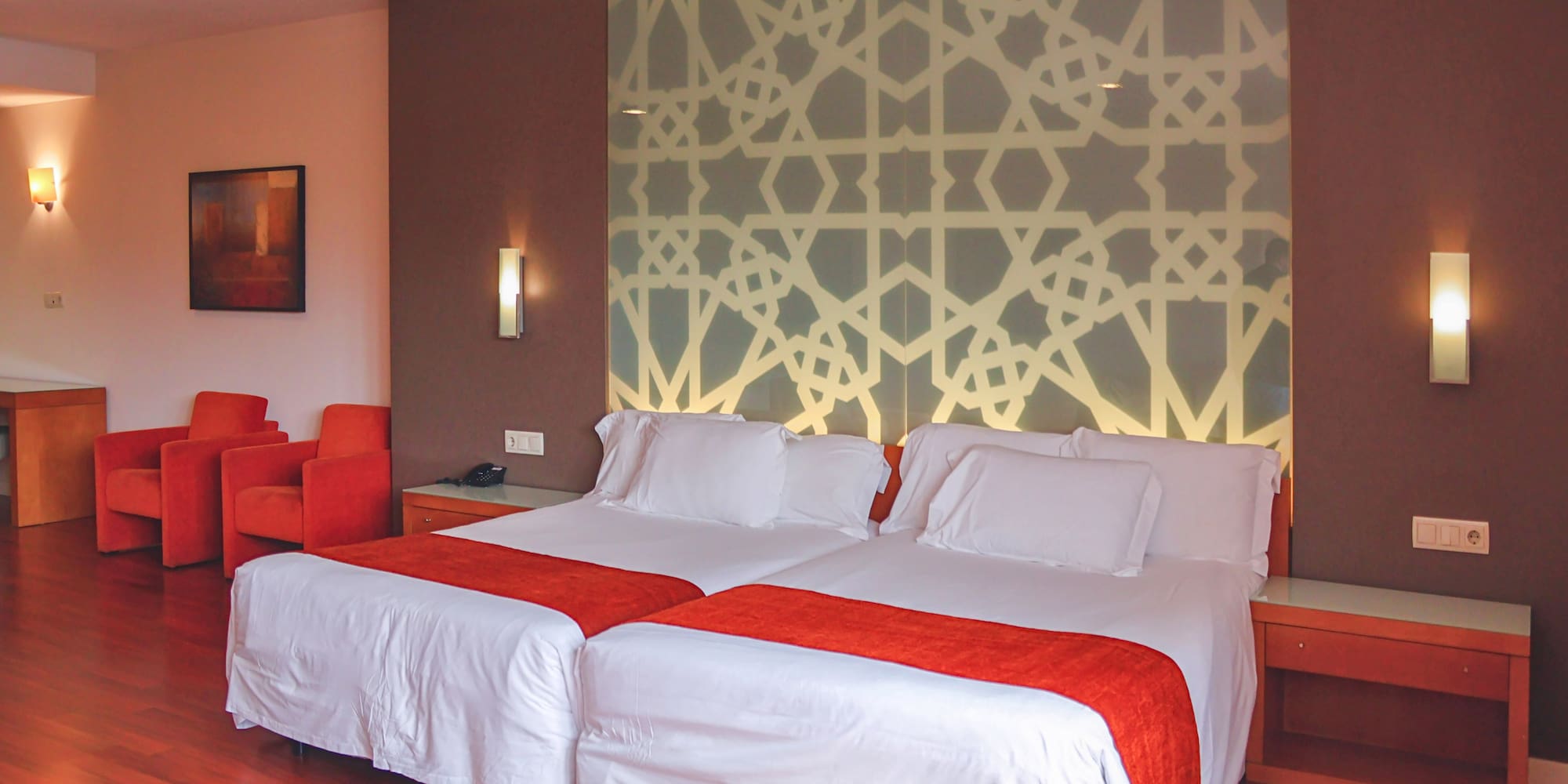 a bed with white sheets and red and orange pillows