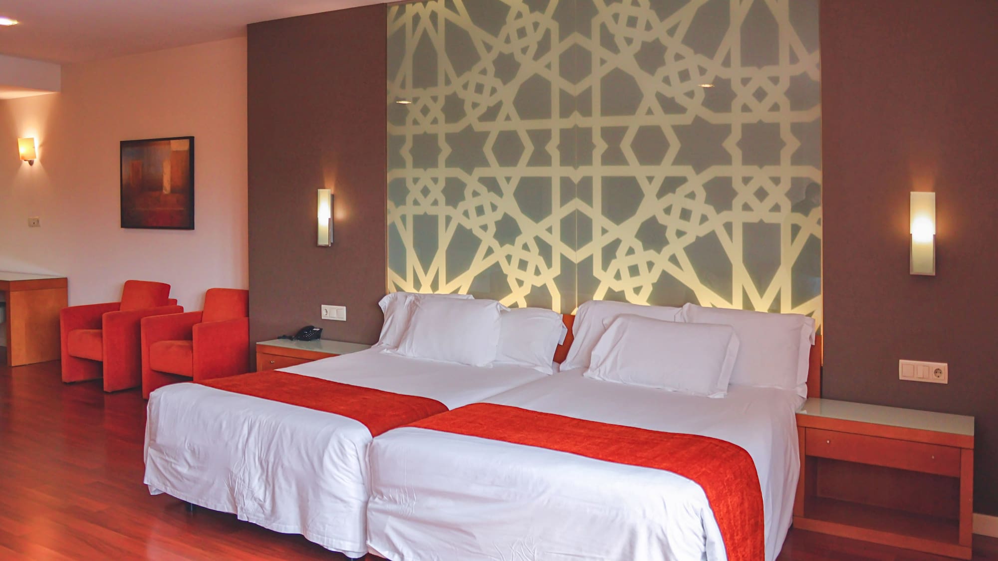 a bed with white sheets and red and orange pillows