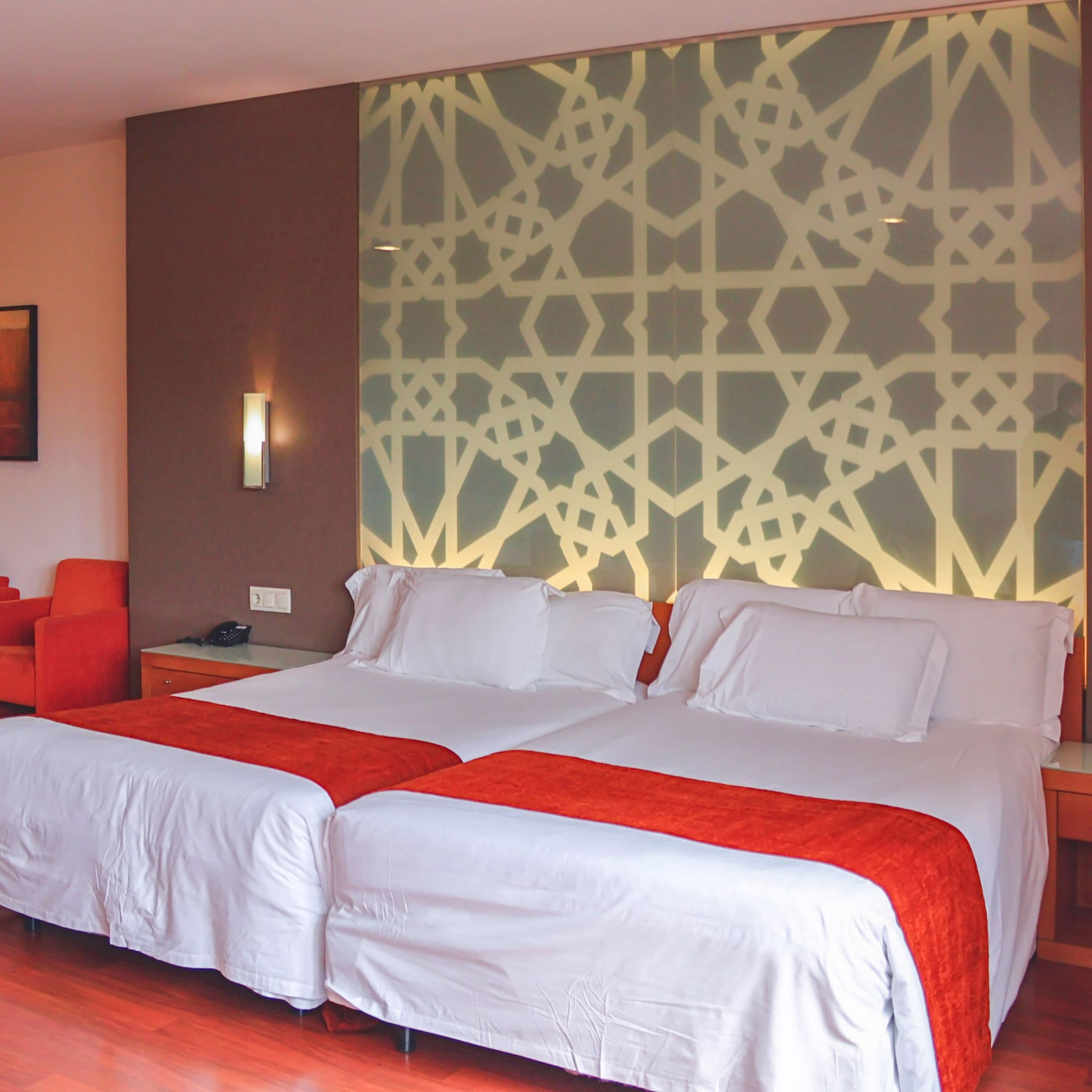 a bed with white sheets and red and orange pillows