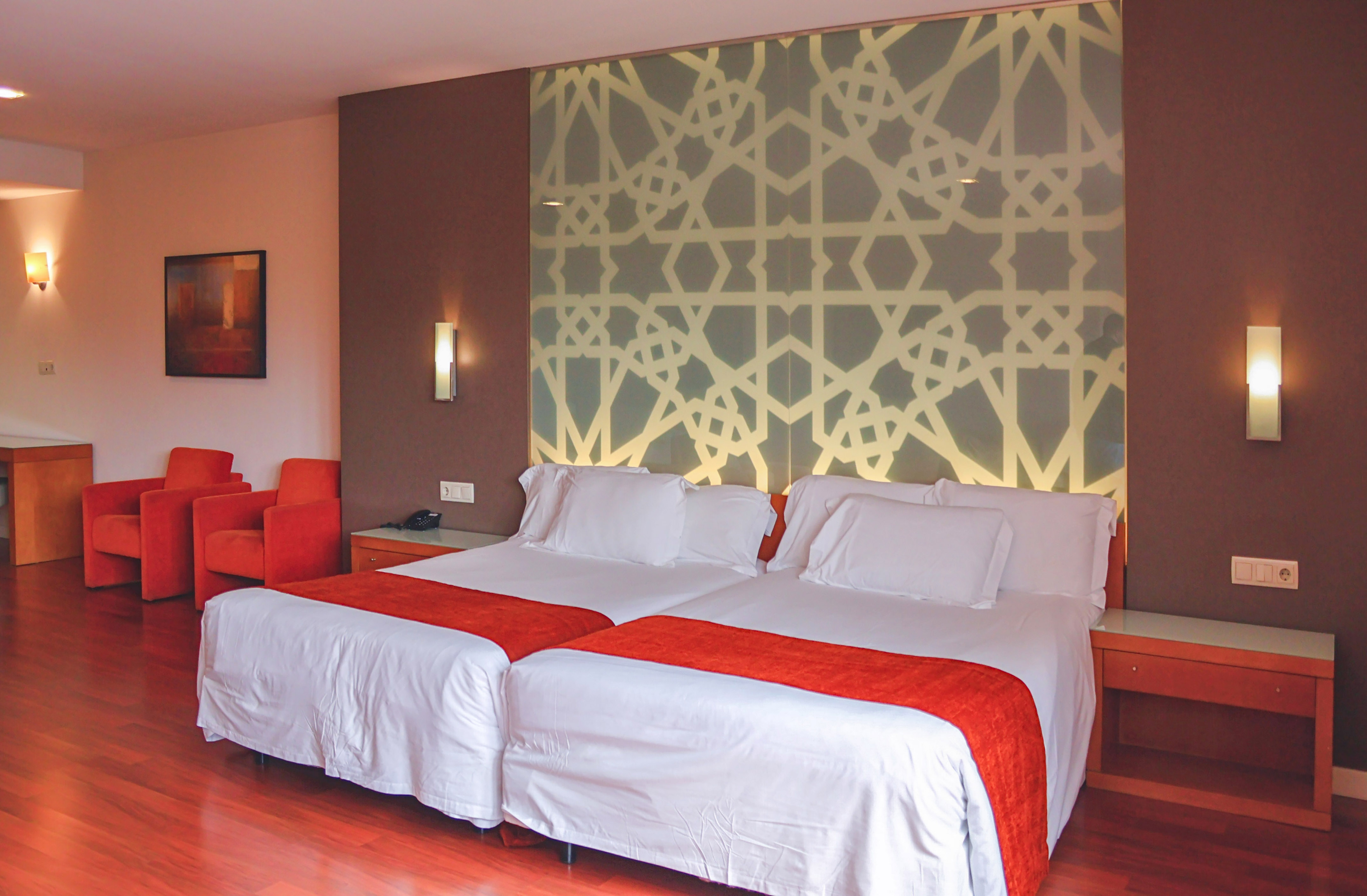 Modern twin hotel room with geometric patterned headboard.