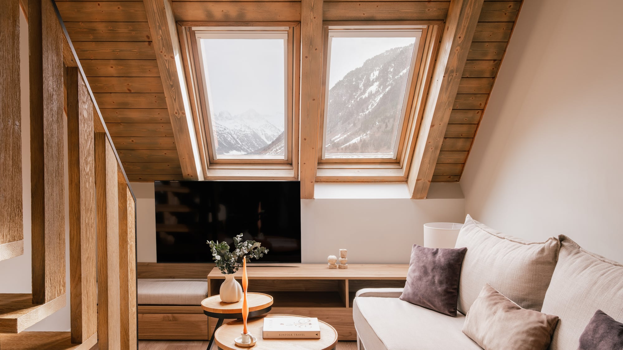 Cozy attic living room with wood beams, mountain view skylights, and sofa.
