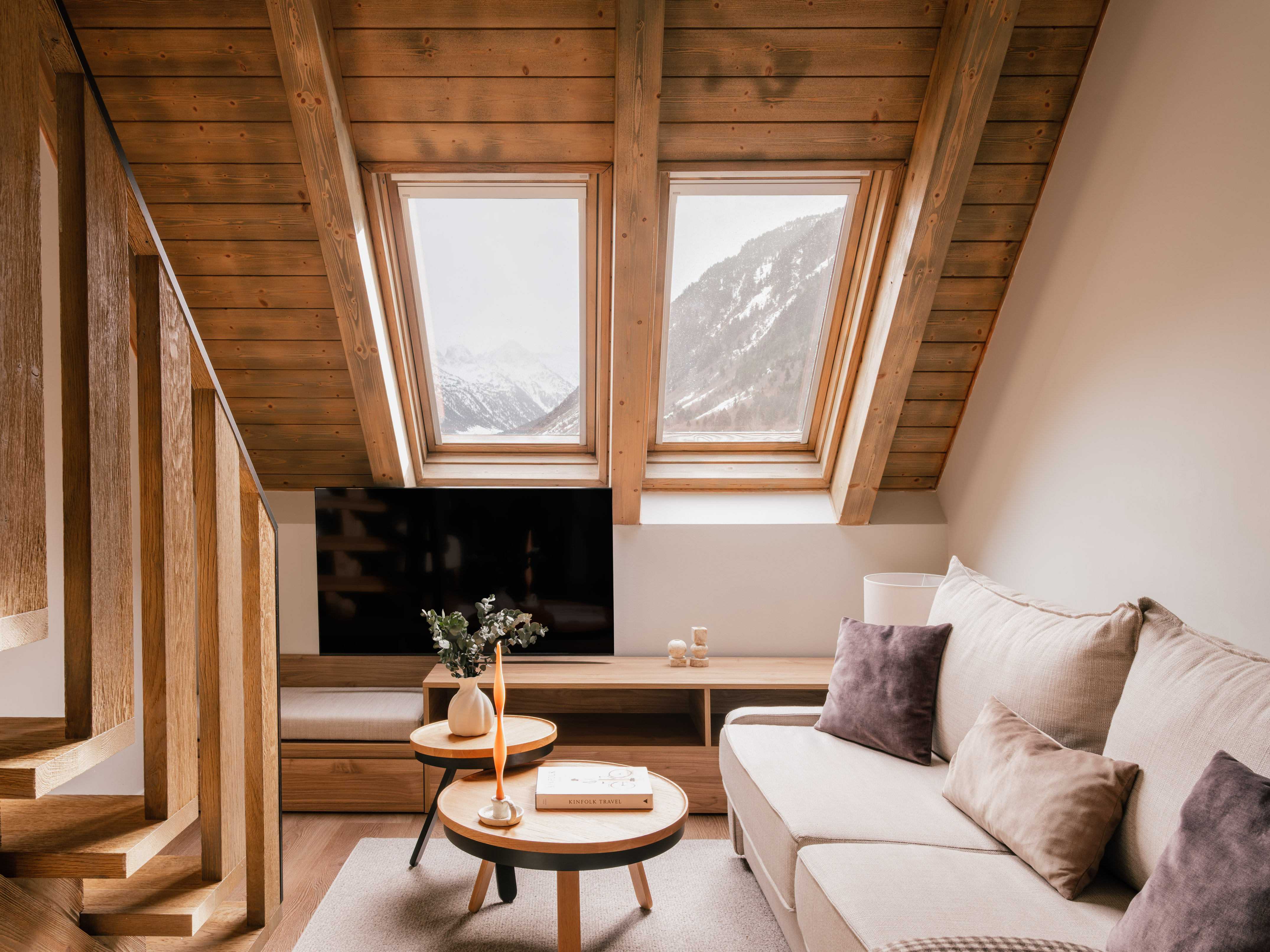 Cozy attic living room with wood beams, mountain view skylights, and sofa.