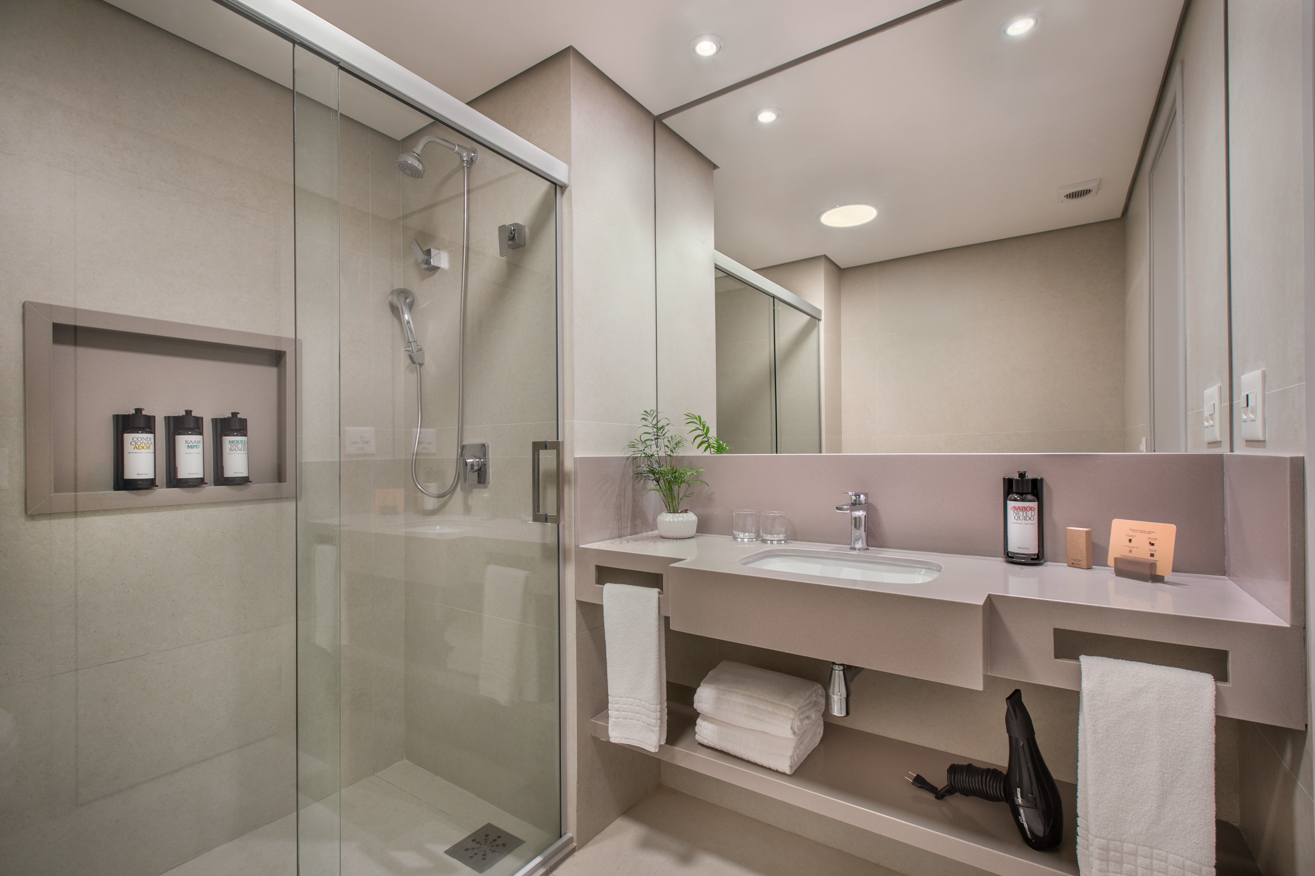 Modern hotel bathroom with glass shower, sleek vanity, and amenities.