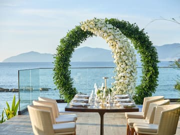 a table set up with chairs and a table set up with a large circular arch with flowers